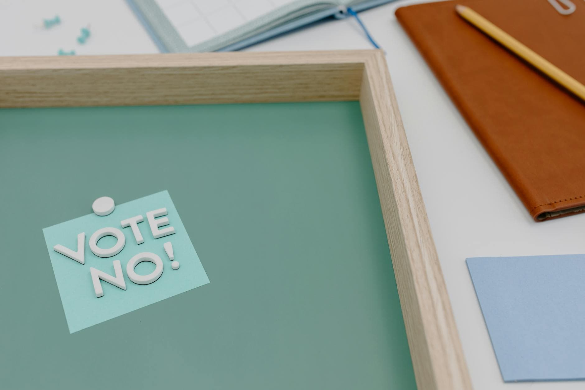Flat lay of a vote no sign on a creative desk setup with office supplies.