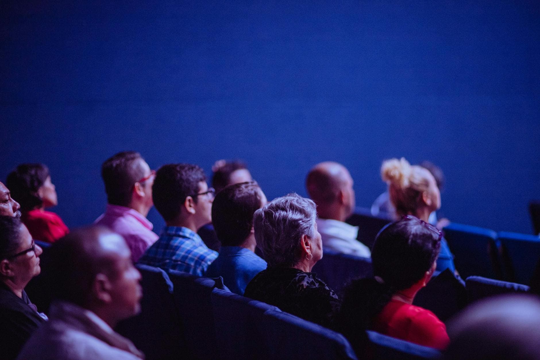 An attentive group of adults seated at an indoor conference, focusing on a presentation.