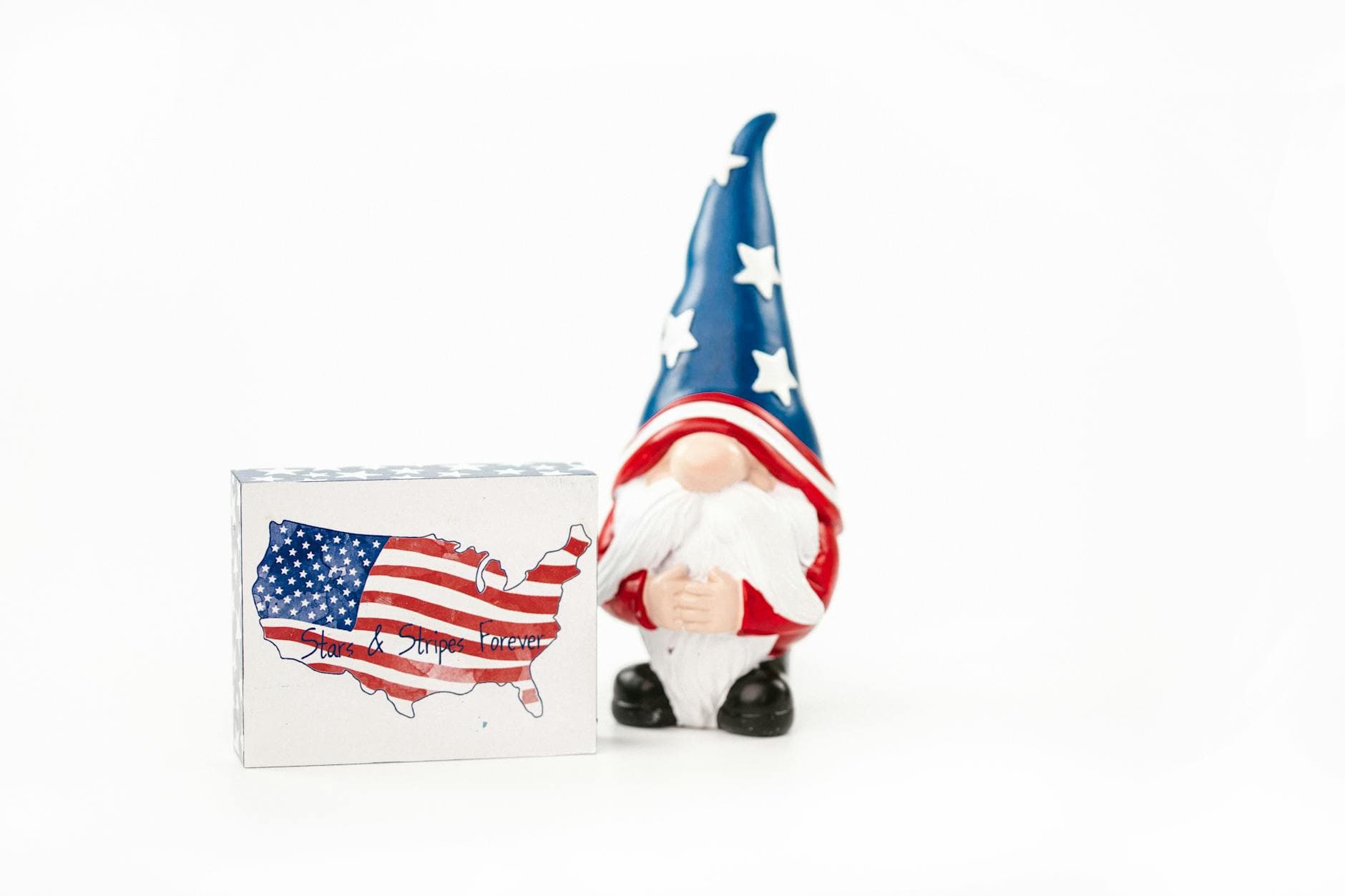 A whimsical gnome in USA colors next to a stars and stripes forever box.