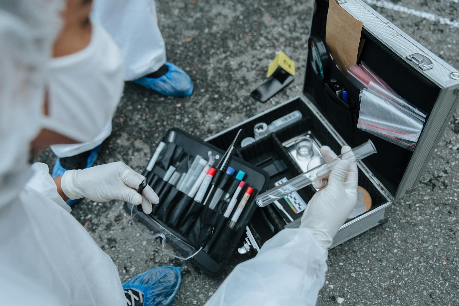 Forensic expert examining evidence with tools at a crime scene investigation outdoors.
