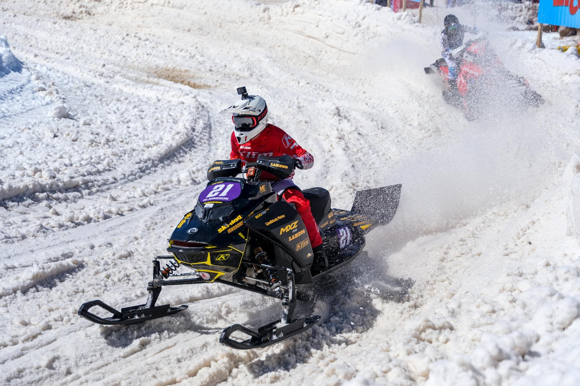 Exciting snowmobile race with riders navigating a snowy track, showcasing speed and winter sports action.