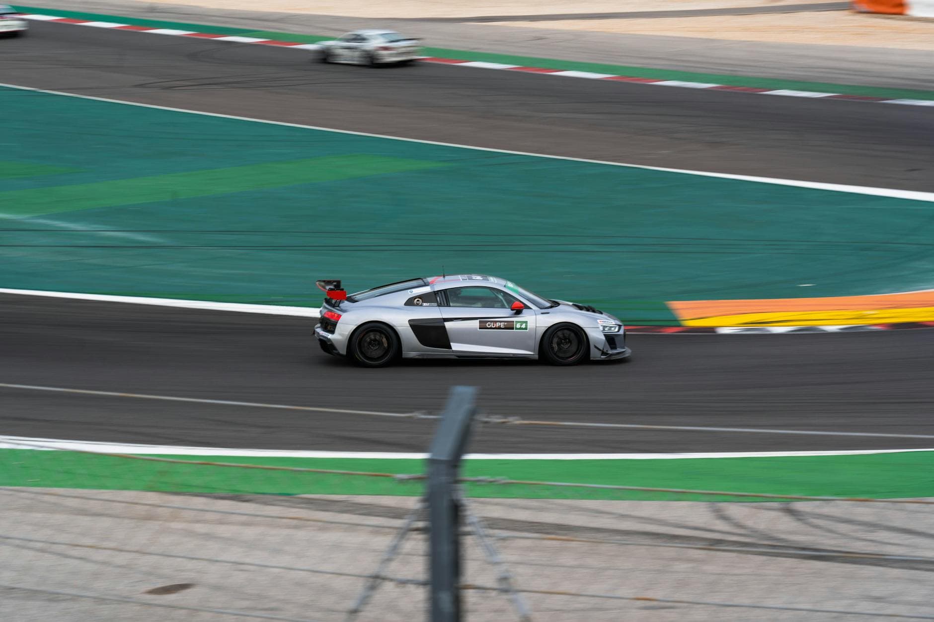 A sleek racing car speeds around a track during a motorsport competition.