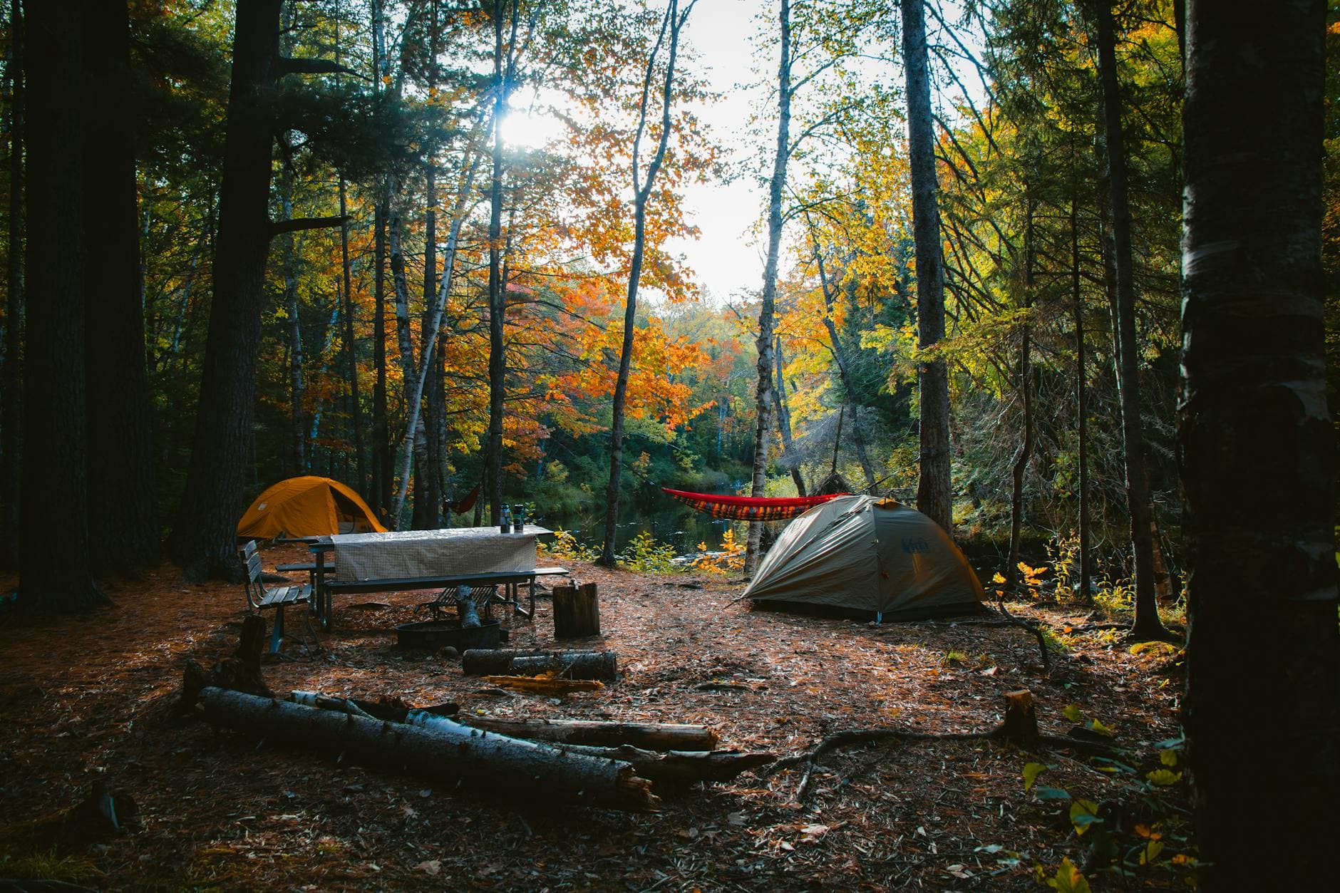 A serene camping site in a colorful autumn forest in Wisconsin, featuring tents and campfire setup.