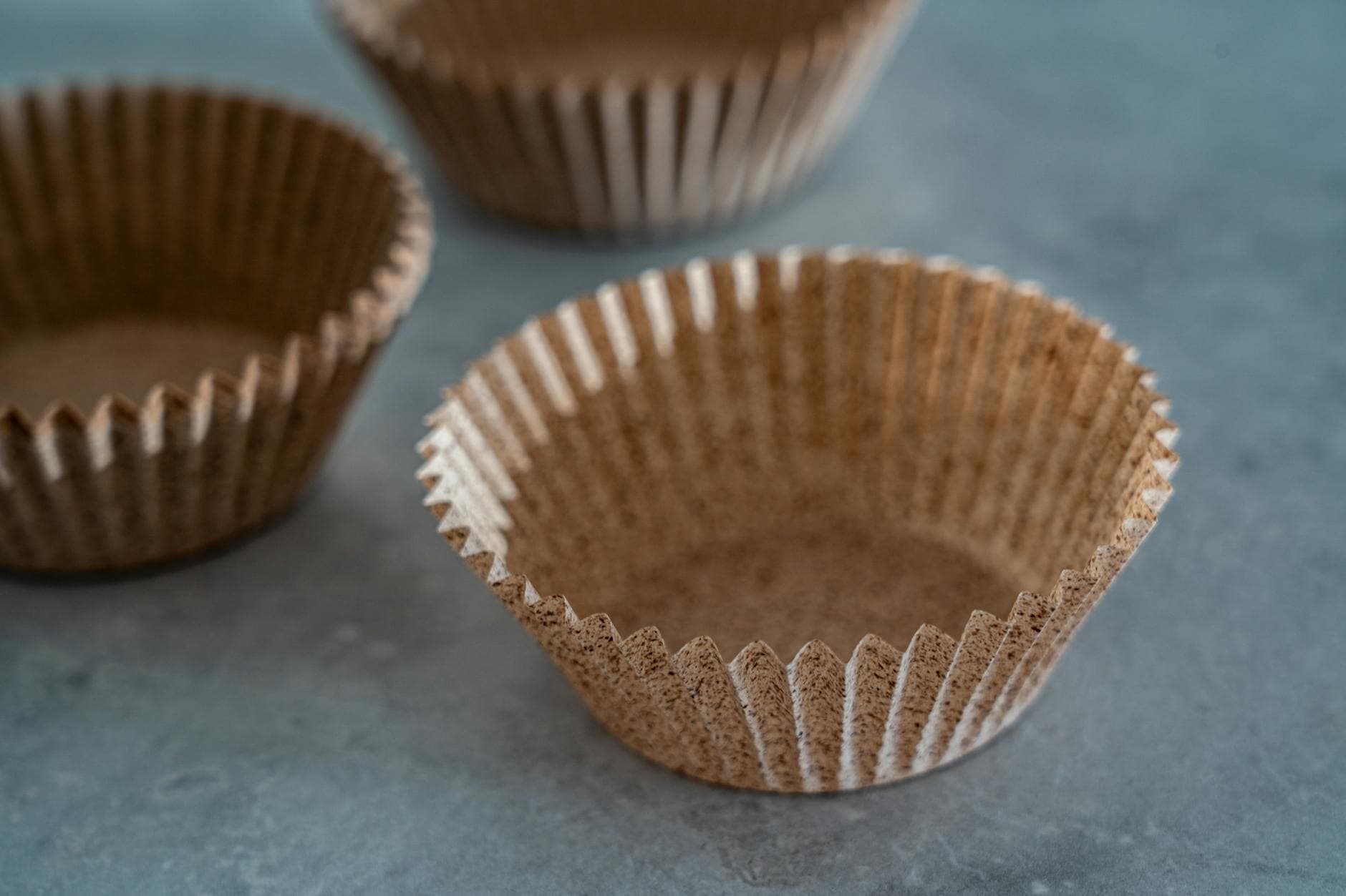 Close-up of empty brown baking cups arranged on a gray surface, perfect for homemade desserts.