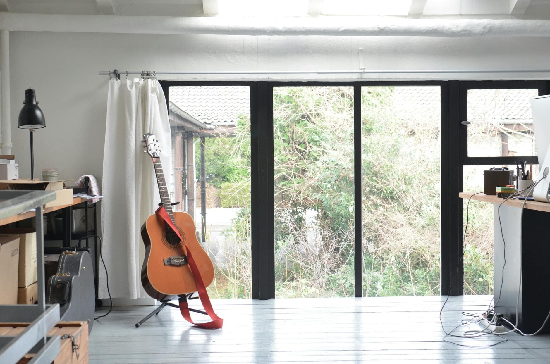 Interior of room with big glass doors tables and guitar on floor stand