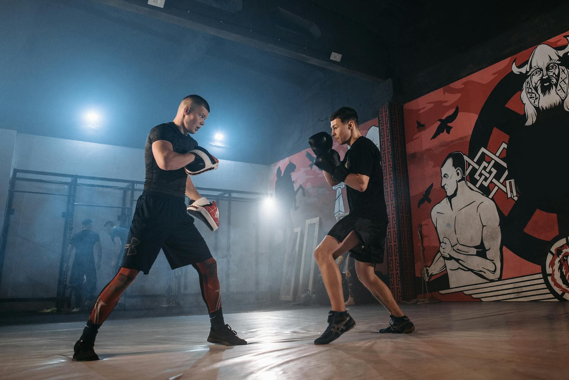 Focused boxers engage in intense mitt drills within a gym setting, highlighting the essence of combat sport training.