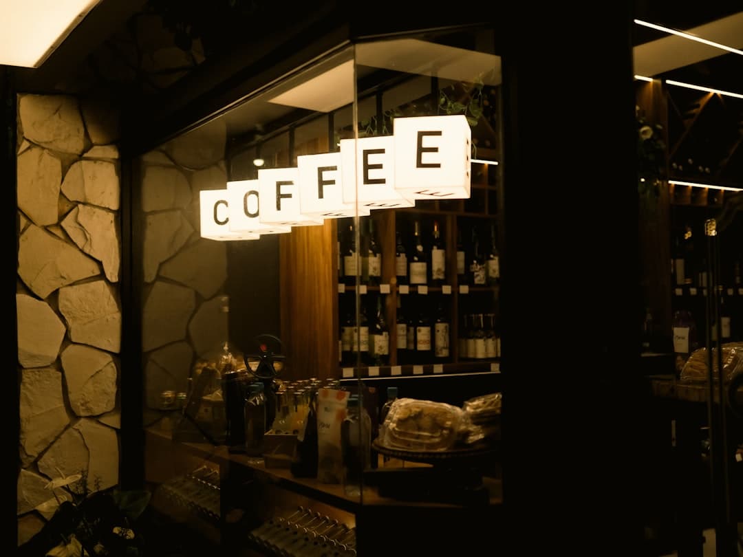 Coffee sign illuminated above bar with bottles.