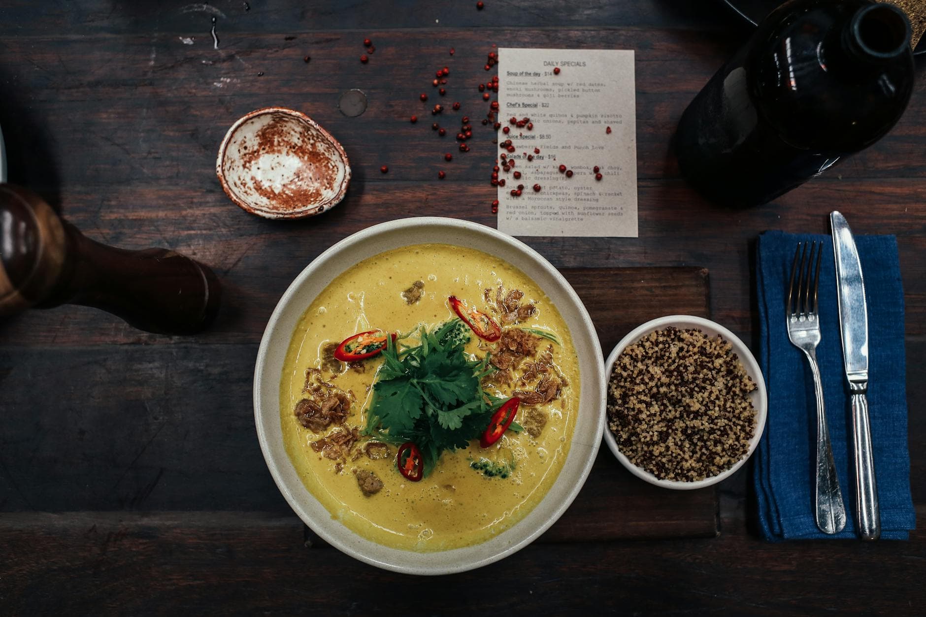 Delicious spicy curry soup with quinoa and fresh herbs served on a rustic table.