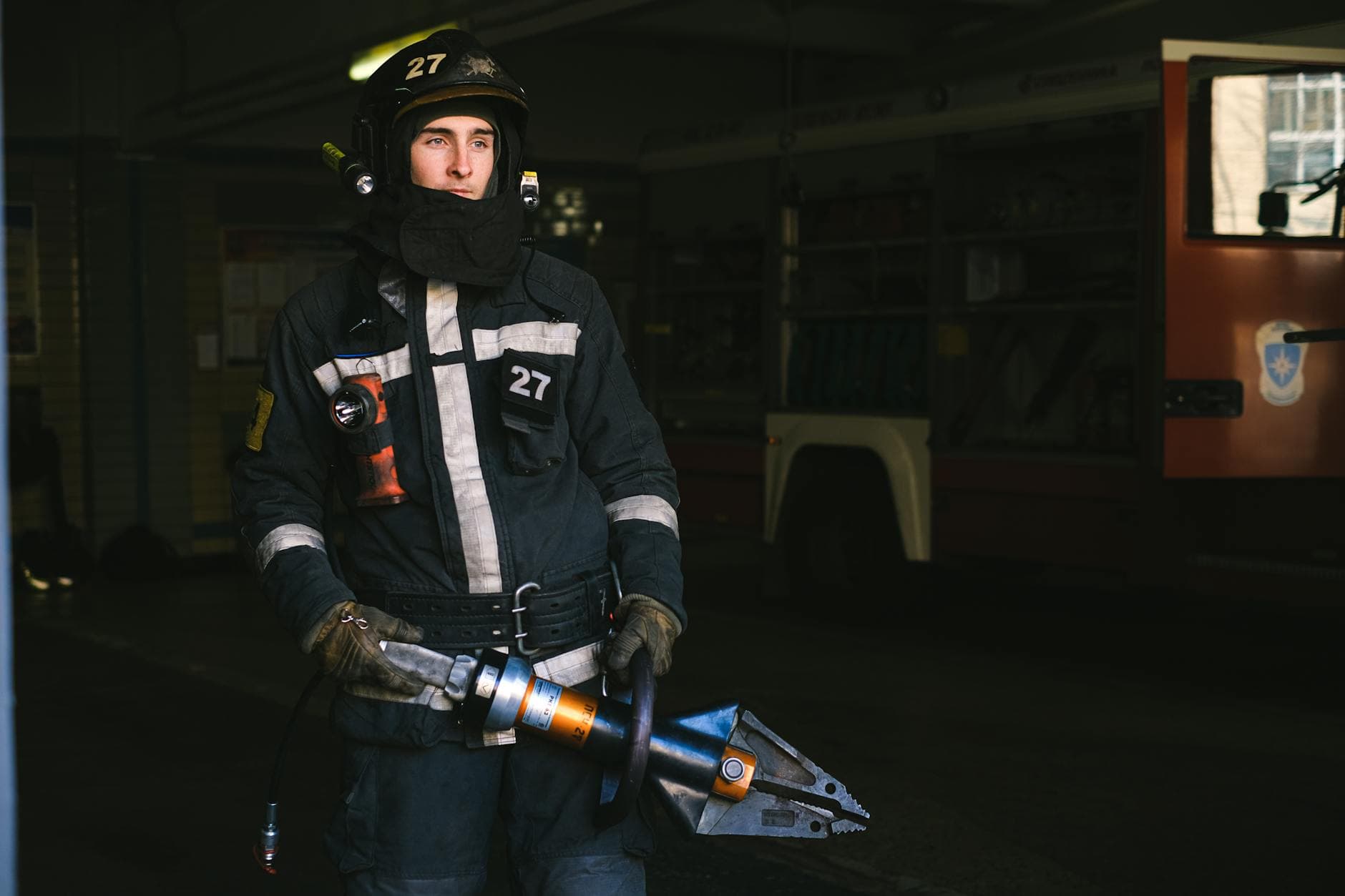 A firefighter wearing a uniform uses a hydraulic tool at a fire station.