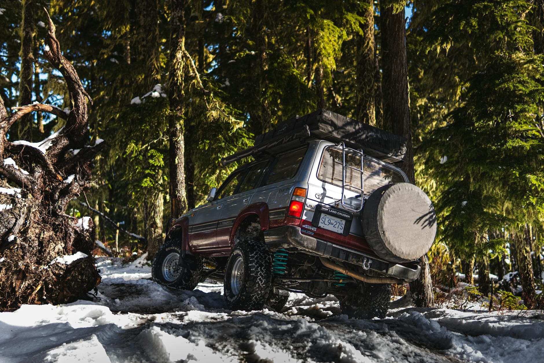 A Toyota Land Cruiser navigating through a snowy forest, showcasing off-road capabilities and adventure spirit.