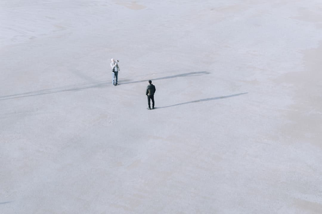 Two people stand far apart on a vast, flat expanse.