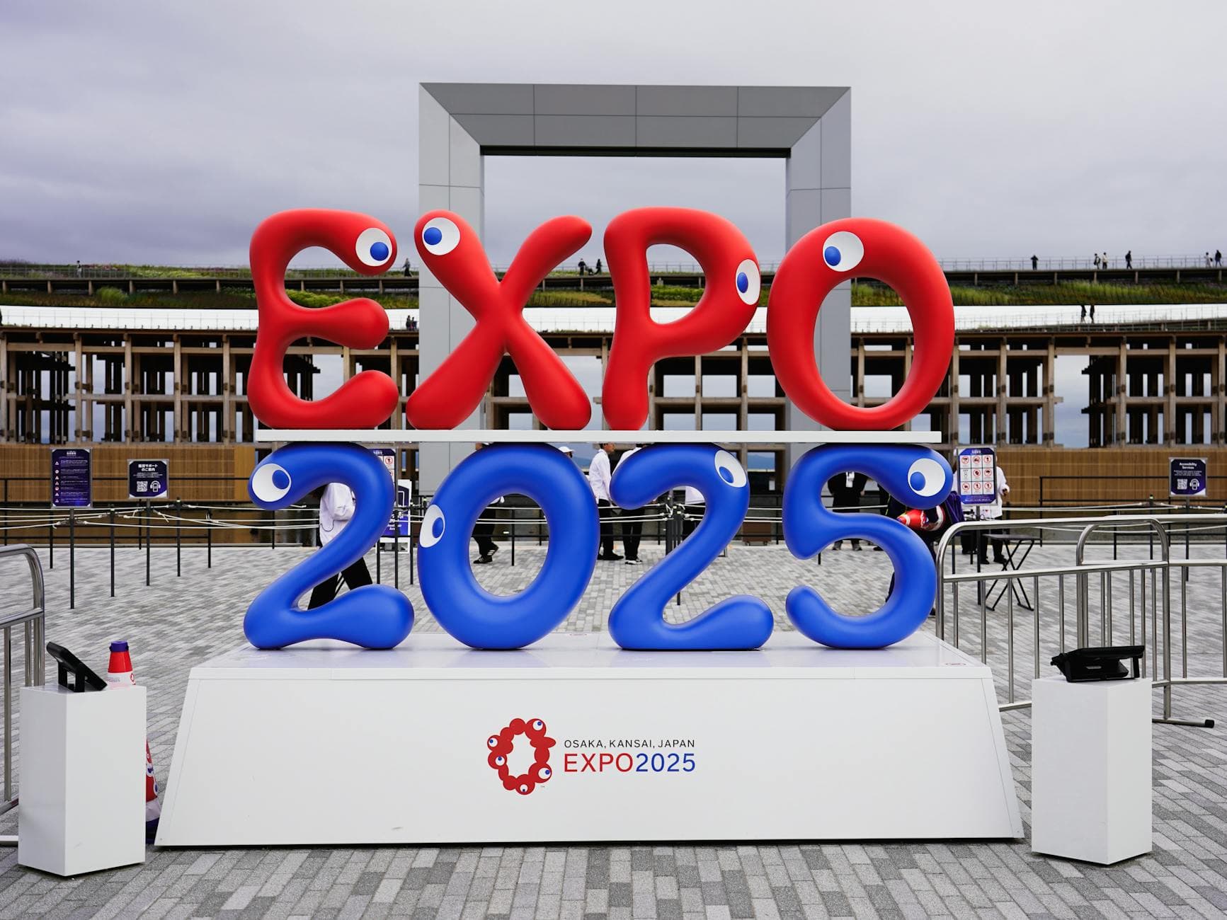 Colorful EXPO 2025 sign at the event site in Osaka, Japan, with modern architecture in the background.