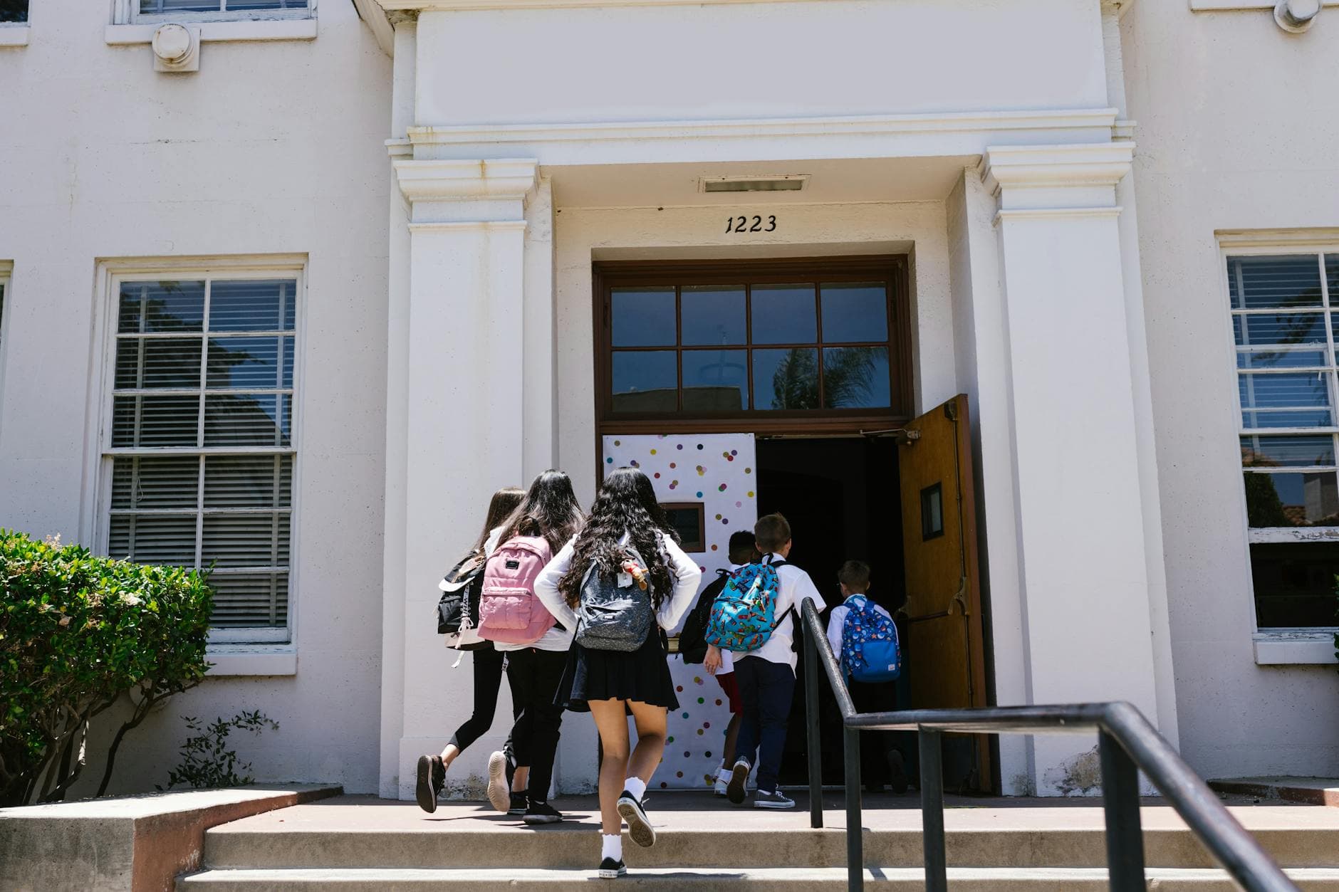 Group of students with backpacks entering a school building. Perfect for back-to-school themes.