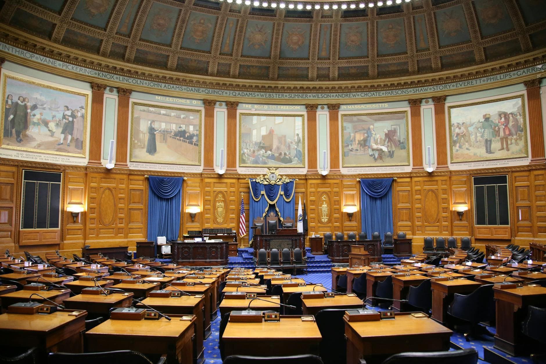 A beautiful view of the Massachusetts State House chamber with elegant decor and empty seating.