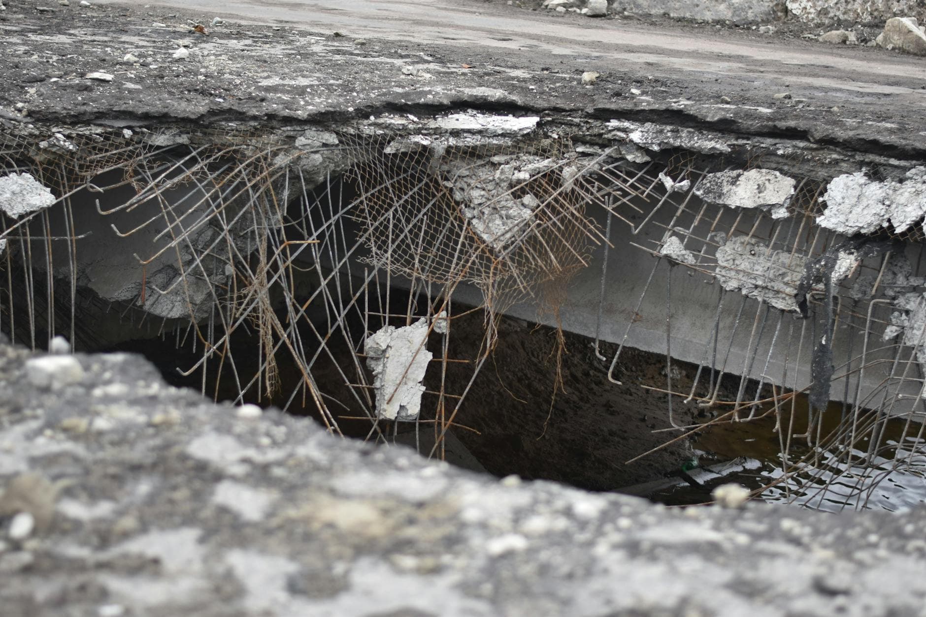 A close-up of a damaged concrete structure with exposed rebar, depicting urban decay.