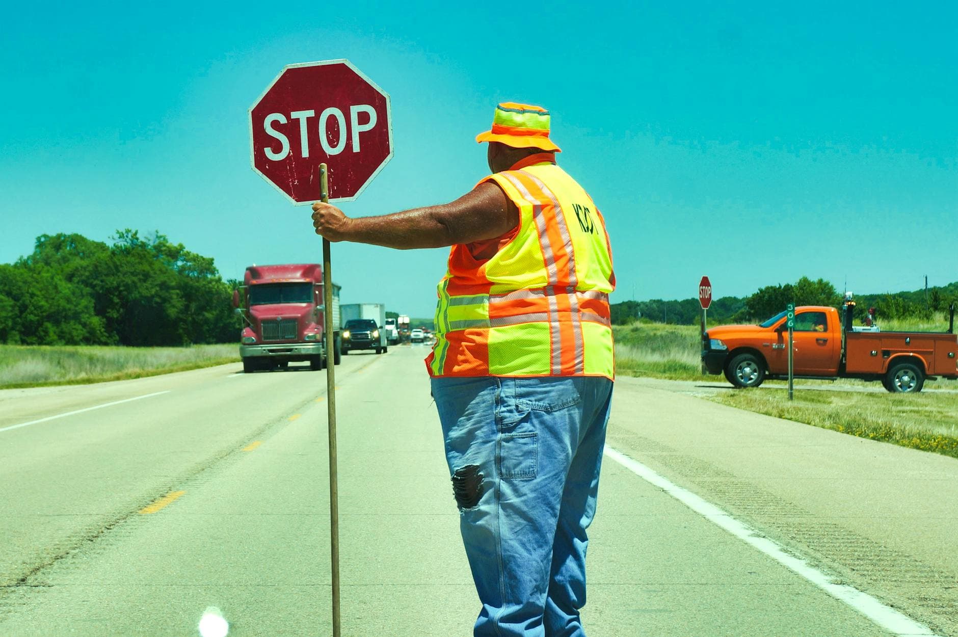 Road construction worker holding a stop sign on a highway ensuring traffic safety.
