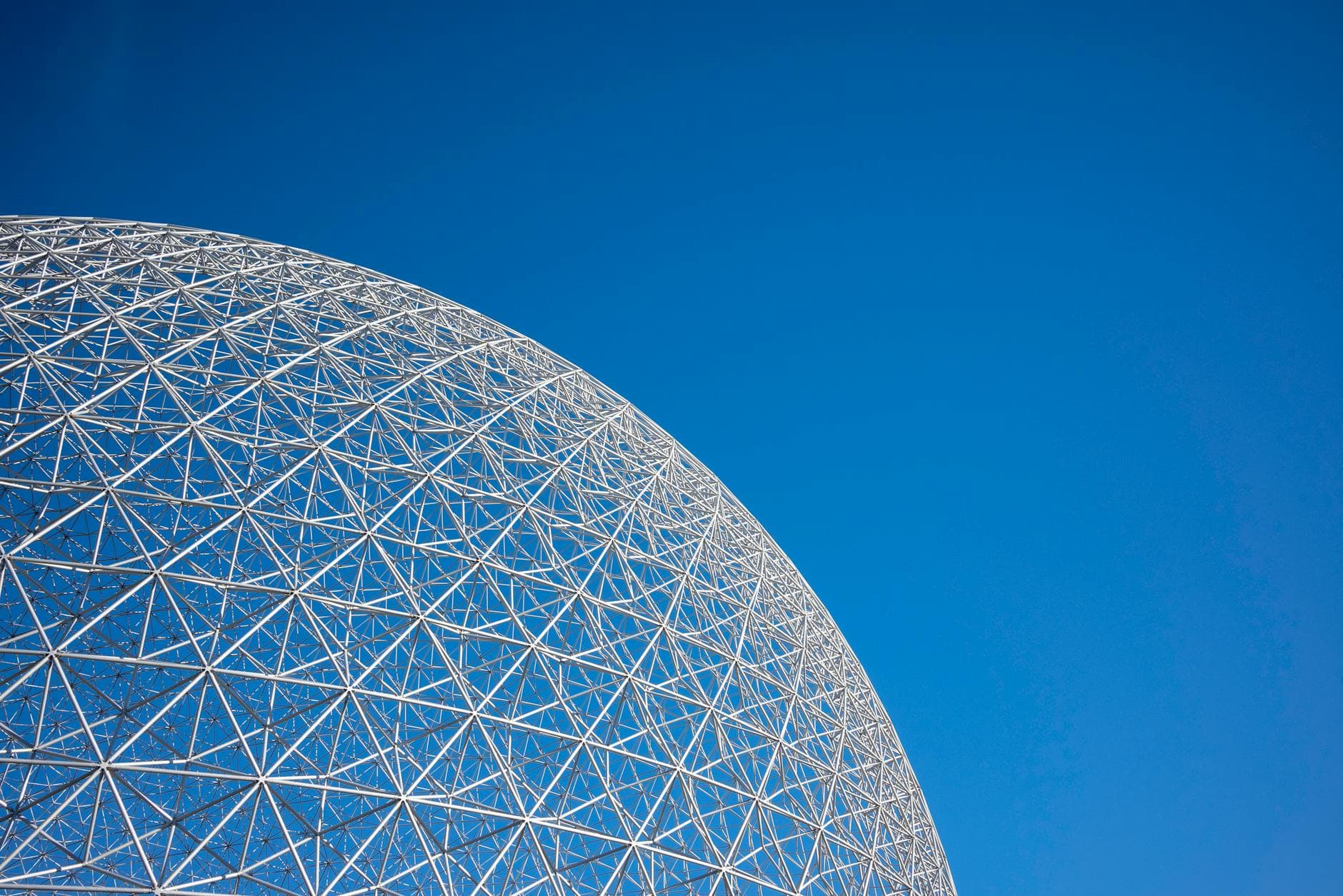 A striking geodesic dome structure set against a clear blue sky, showcasing modern architecture.