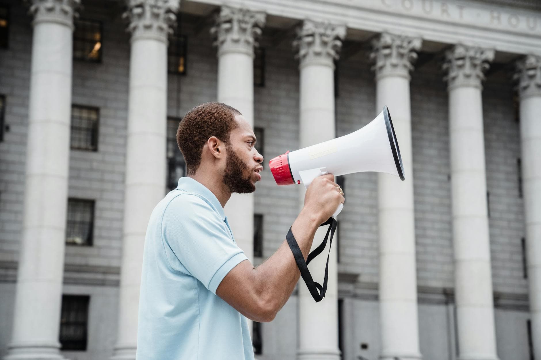 Person using a megaphone in a peaceful protest outside a court building.