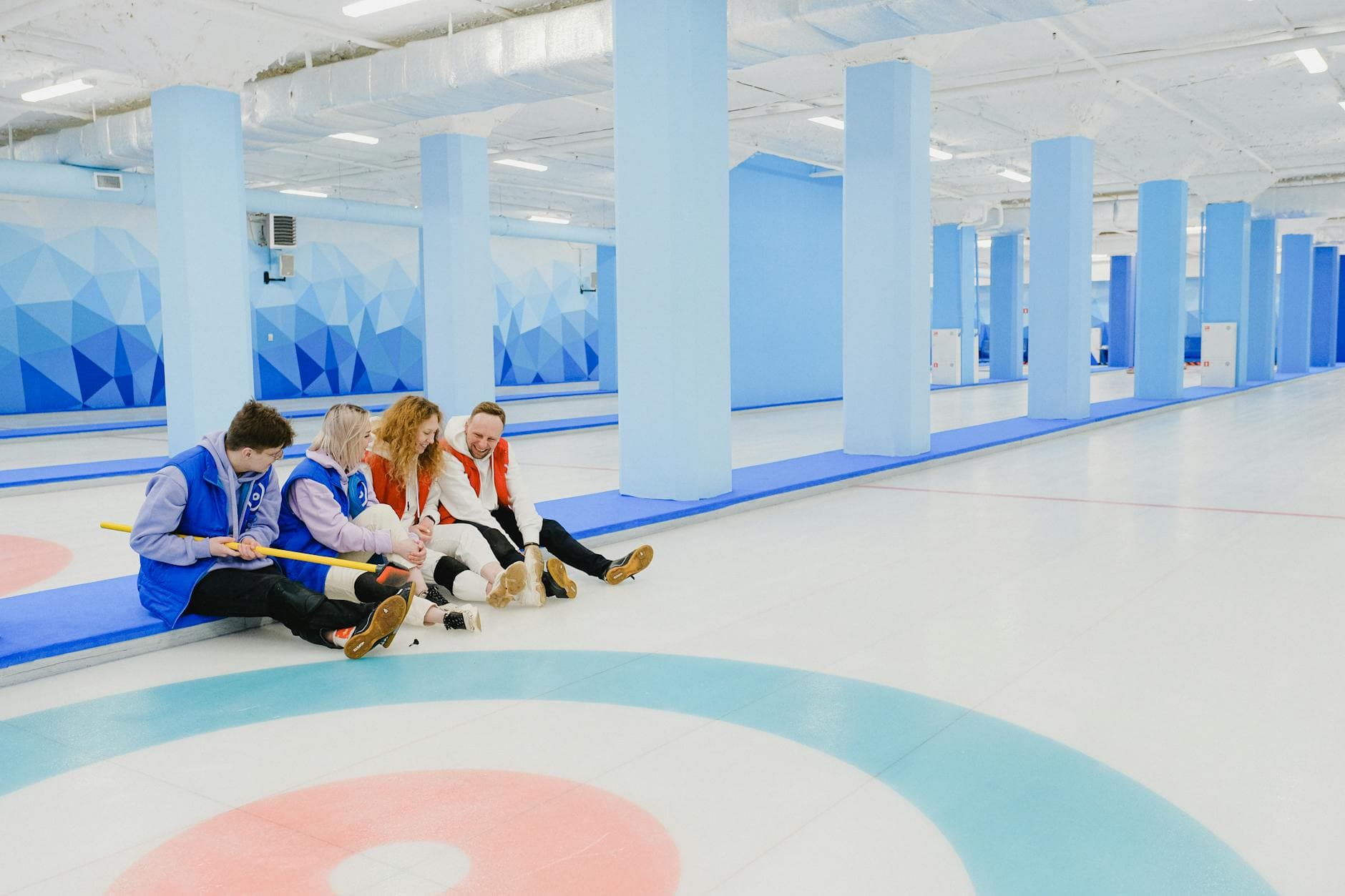 Casual group of curlers relaxing indoors at a vibrant, modern ice rink.