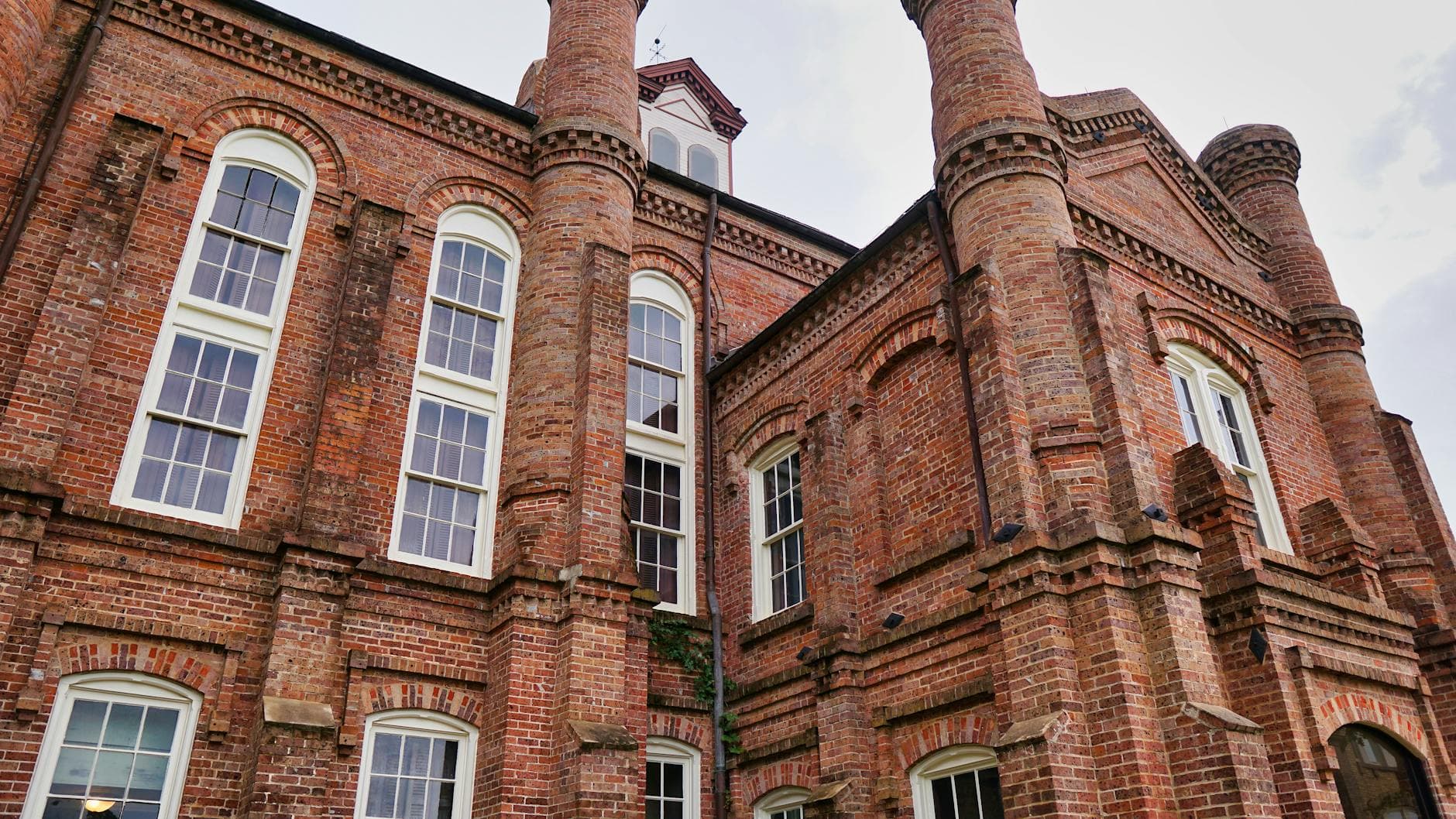 Low-angle shot of a historical brick courthouse featuring arched windows and architectural details.