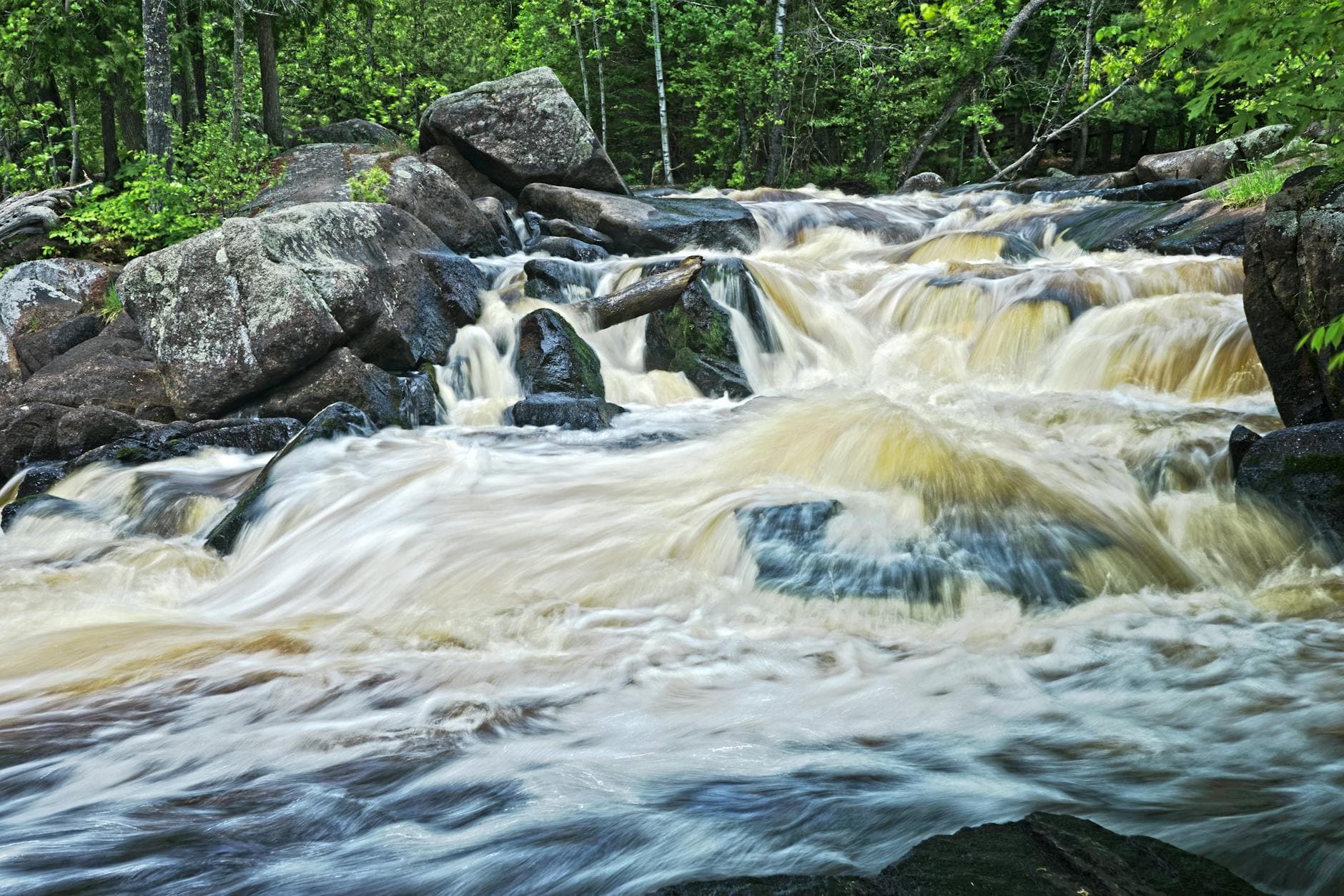 Dynamic waterfall cascading over rocks in a lush forest in Dunbar, WI.