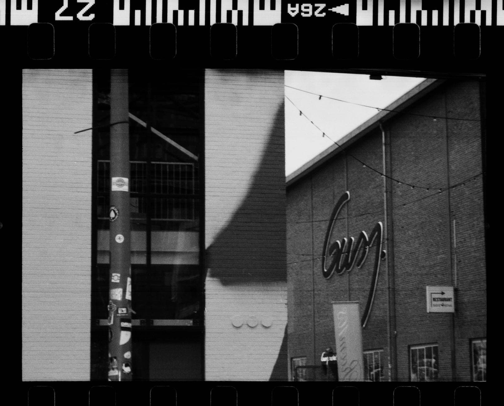 Classic black and white photo of an urban scene featuring signage and brick architecture.