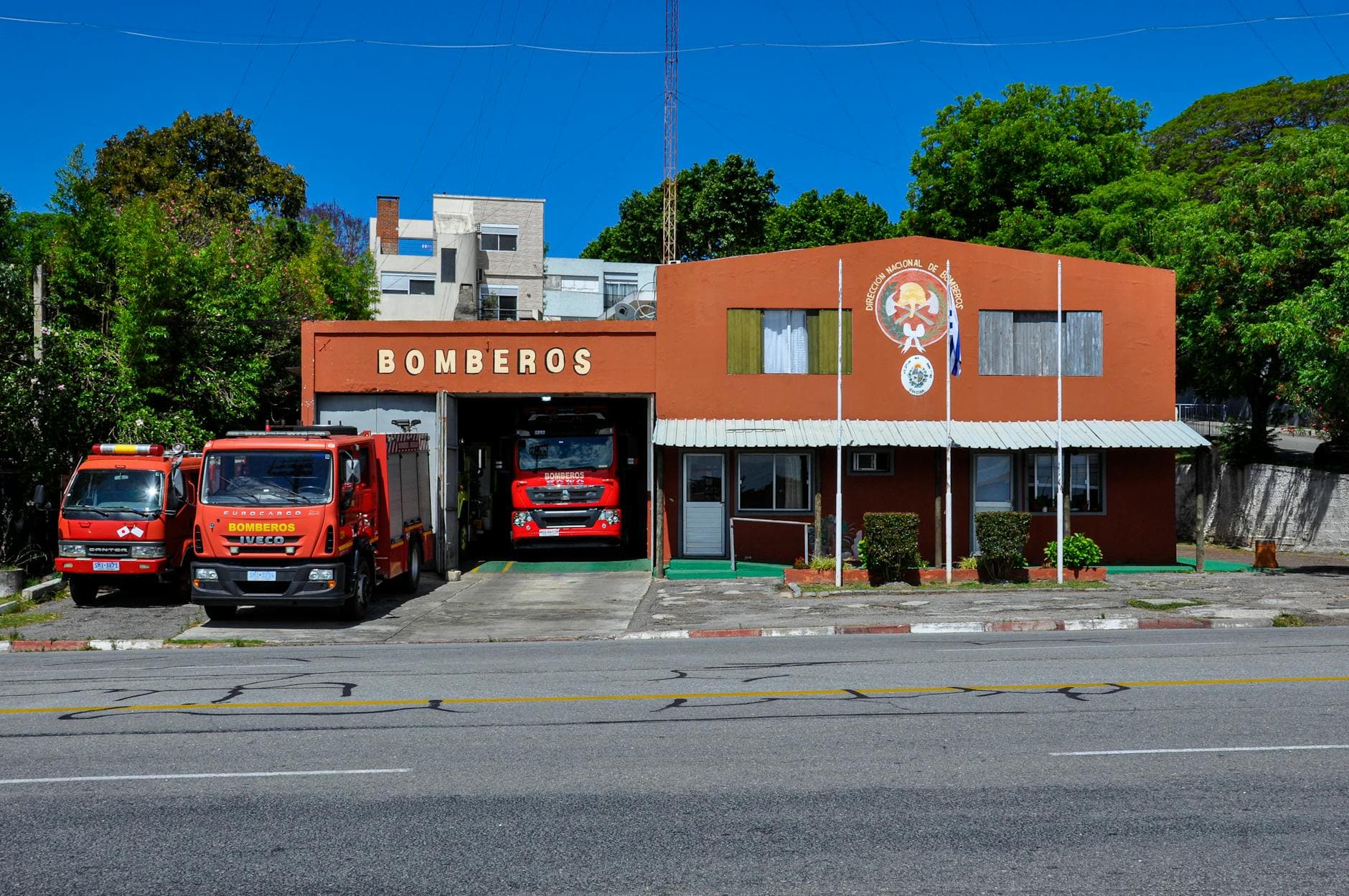 Front view of Colonia del Sacramento fire station with fire trucks parked outside.