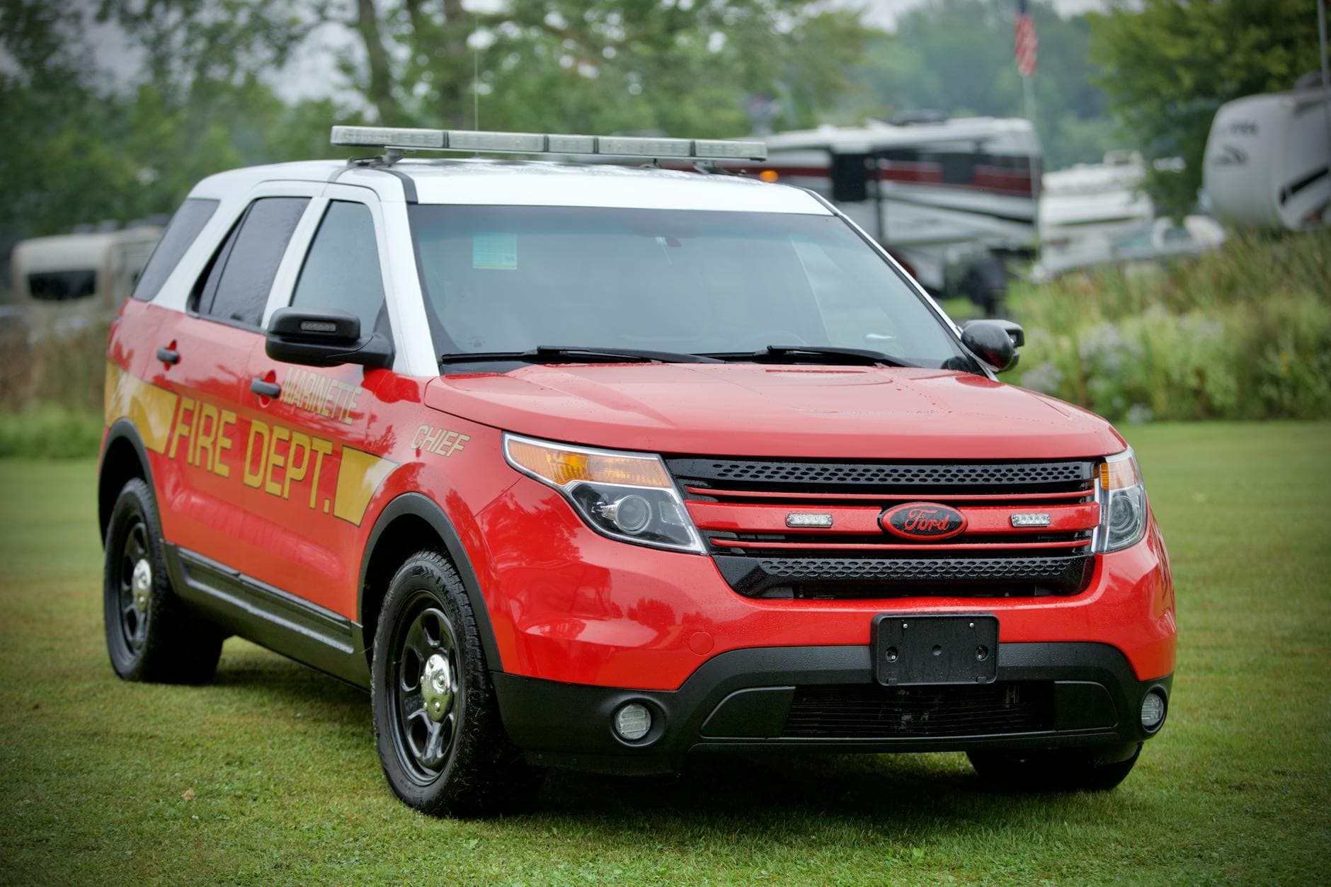Red Ford Explorer fire department vehicle parked on grass, highlighting emergency services.