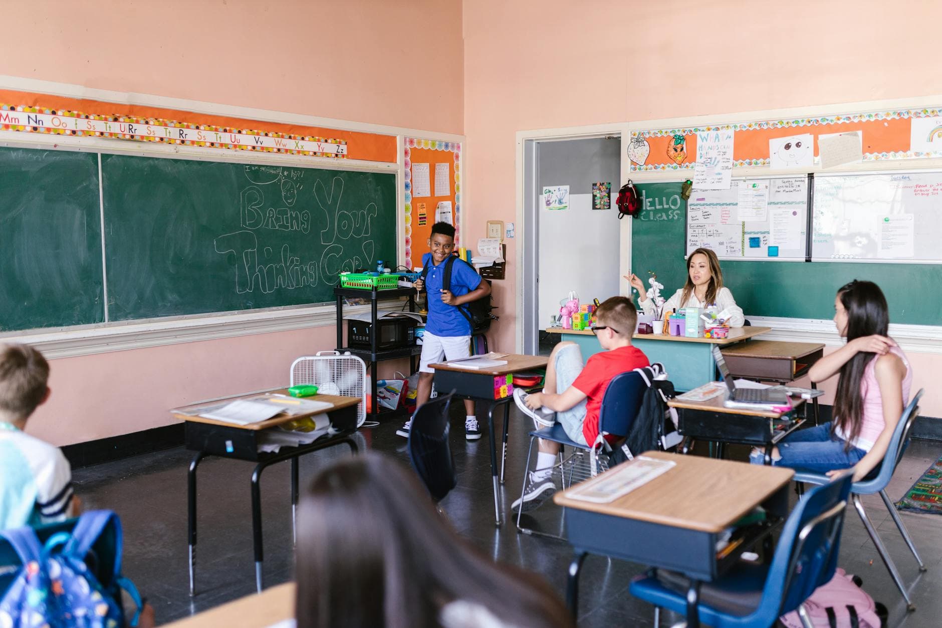 Children in a classroom with a teacher on the first day of school, chalkboard with