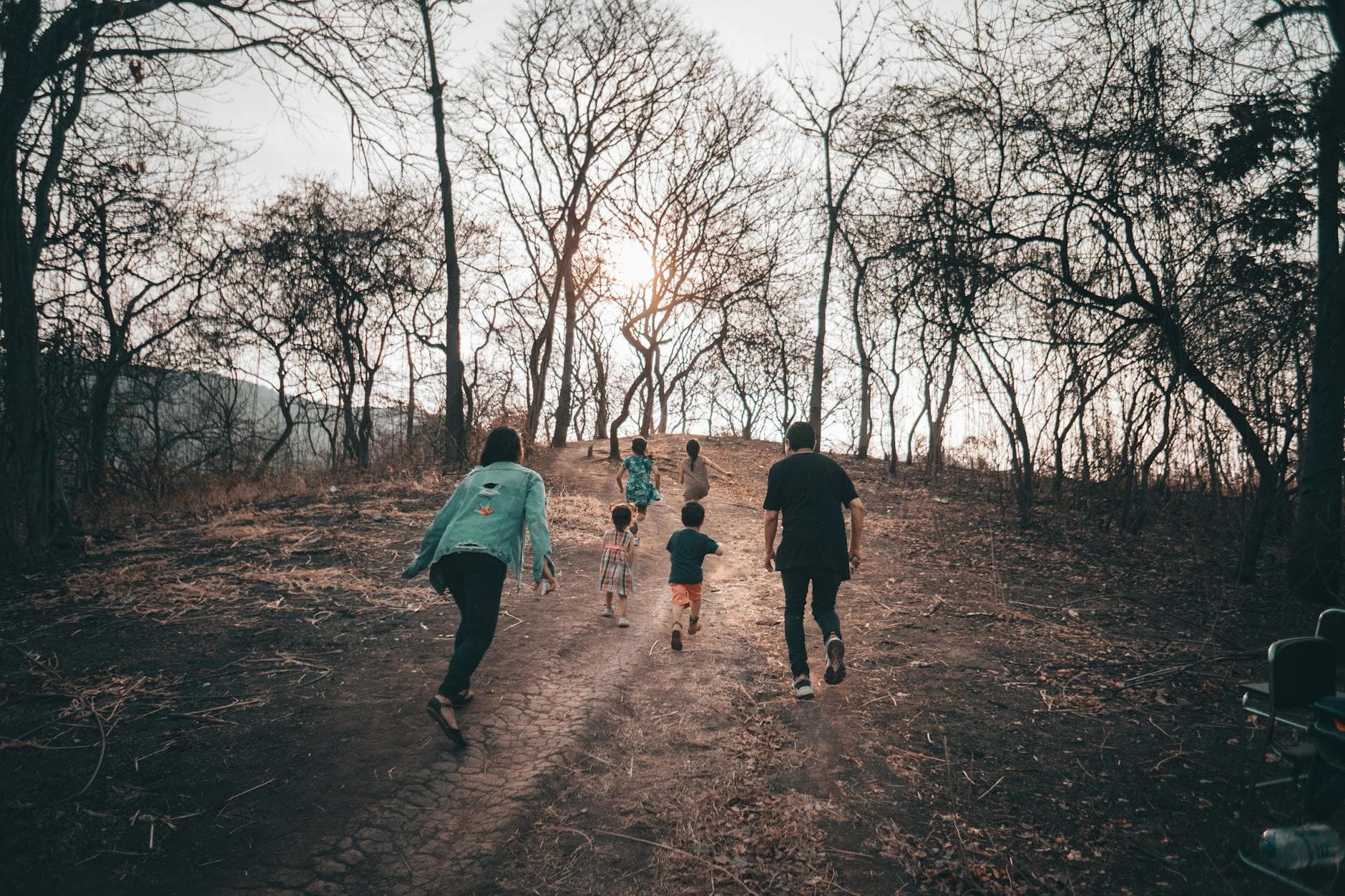 A family enjoying a hike through a bare forest during autumn, creating a memorable outdoor experience together.