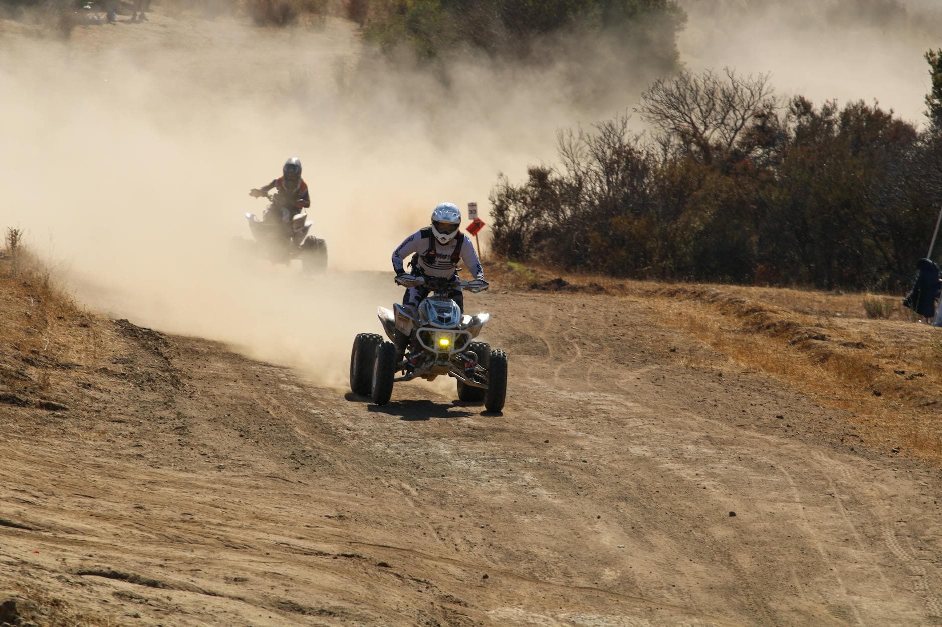 Exciting ATV race on a dusty trail showcasing speed and adventure outdoors.
