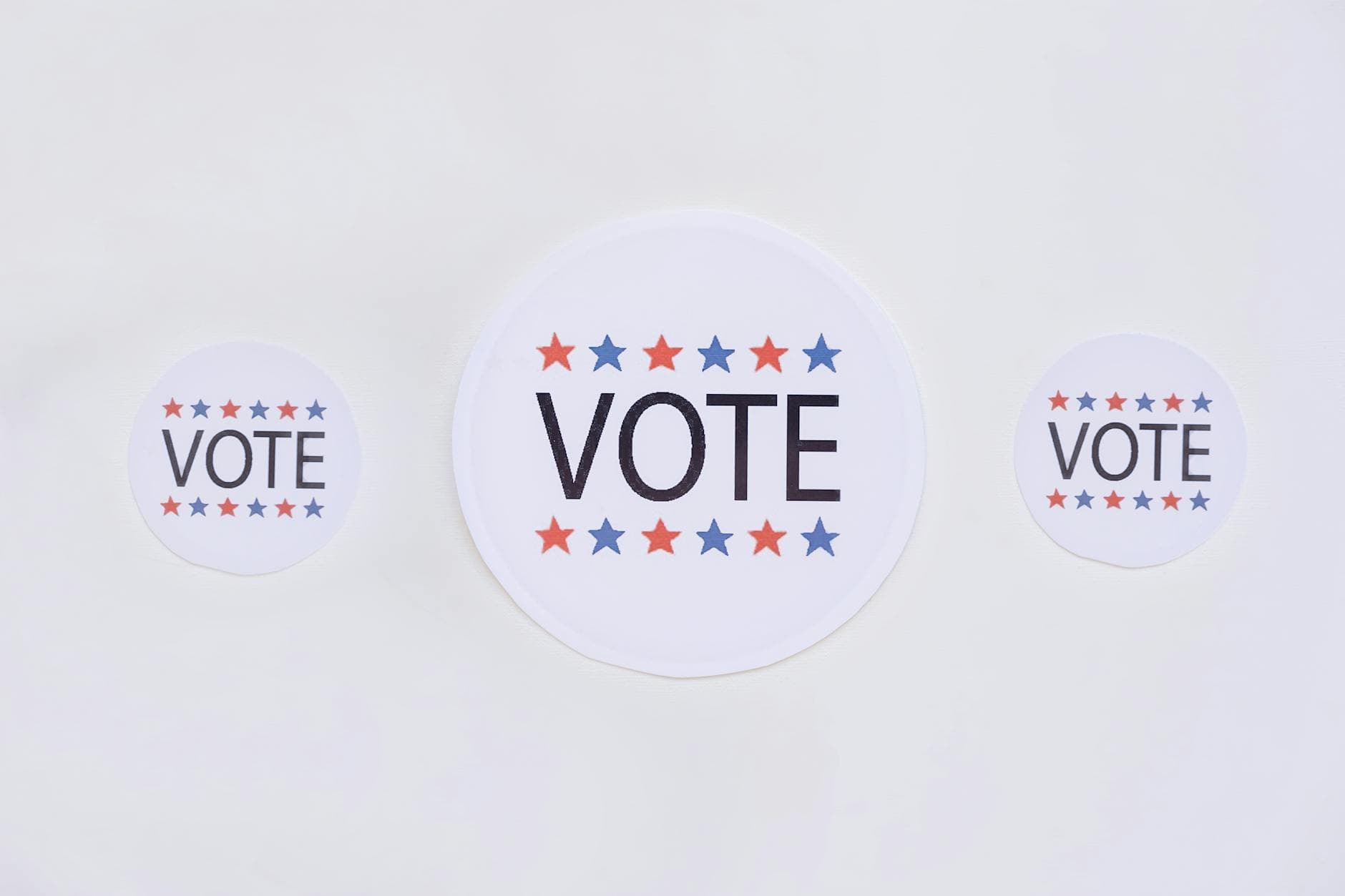 Three vote stickers featuring stars symbolize political participation on a white surface.