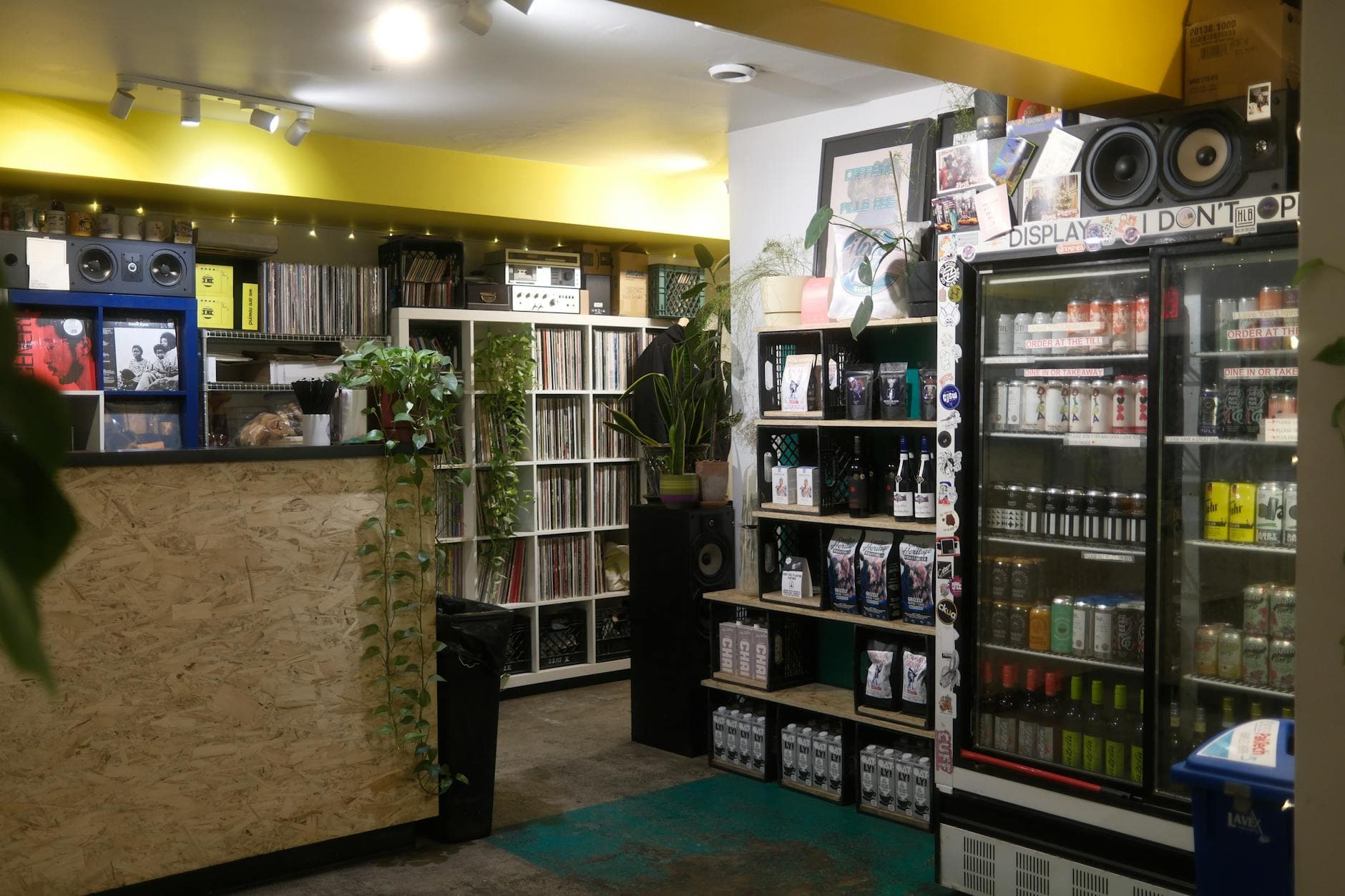 Warm, inviting record shop showcasing vinyl collection, beverages, and plants. Ideal cozy vibe.