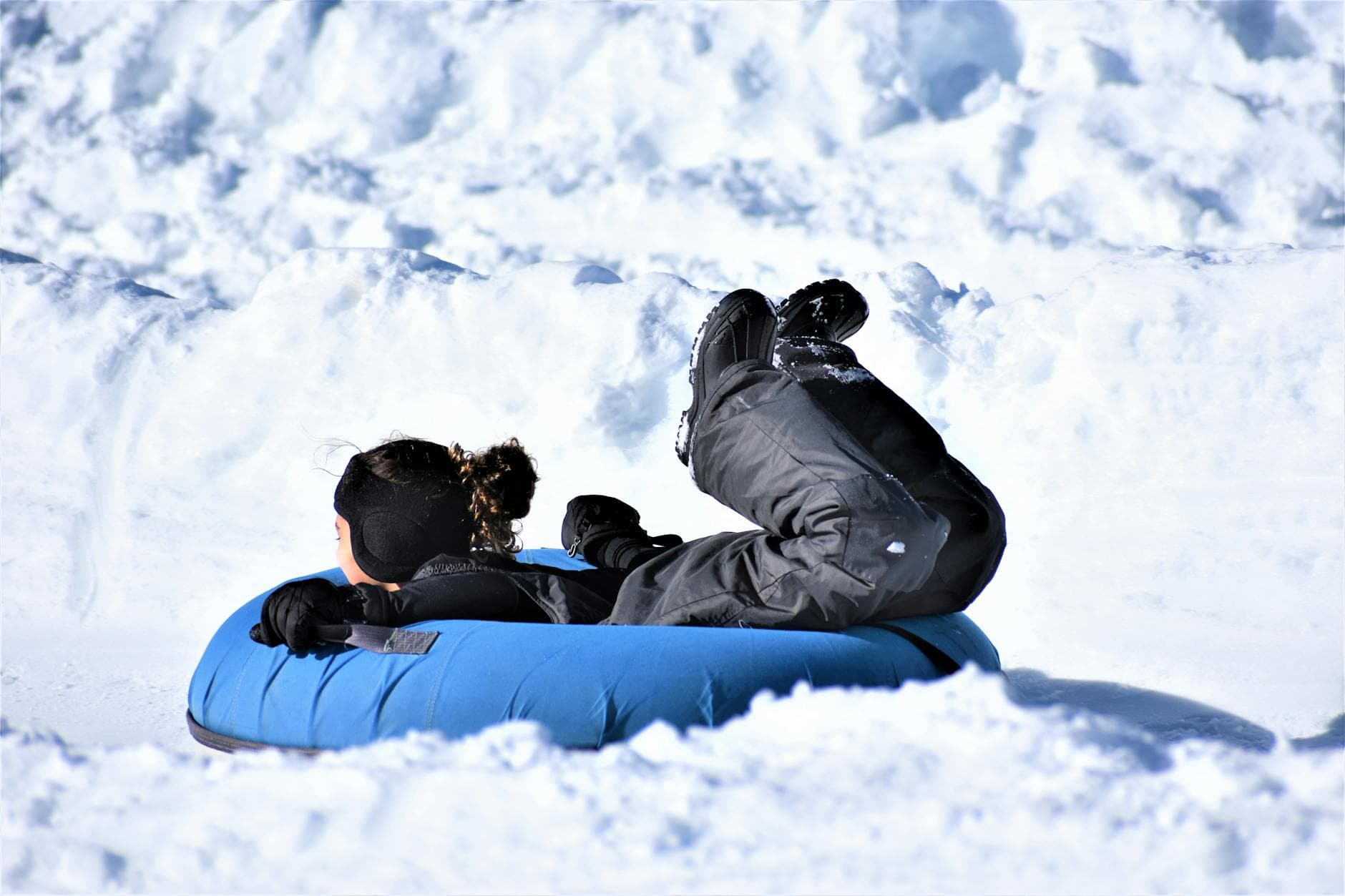 A child enjoys snow tubing down a snowy hill, showcasing winter fun and adventure.