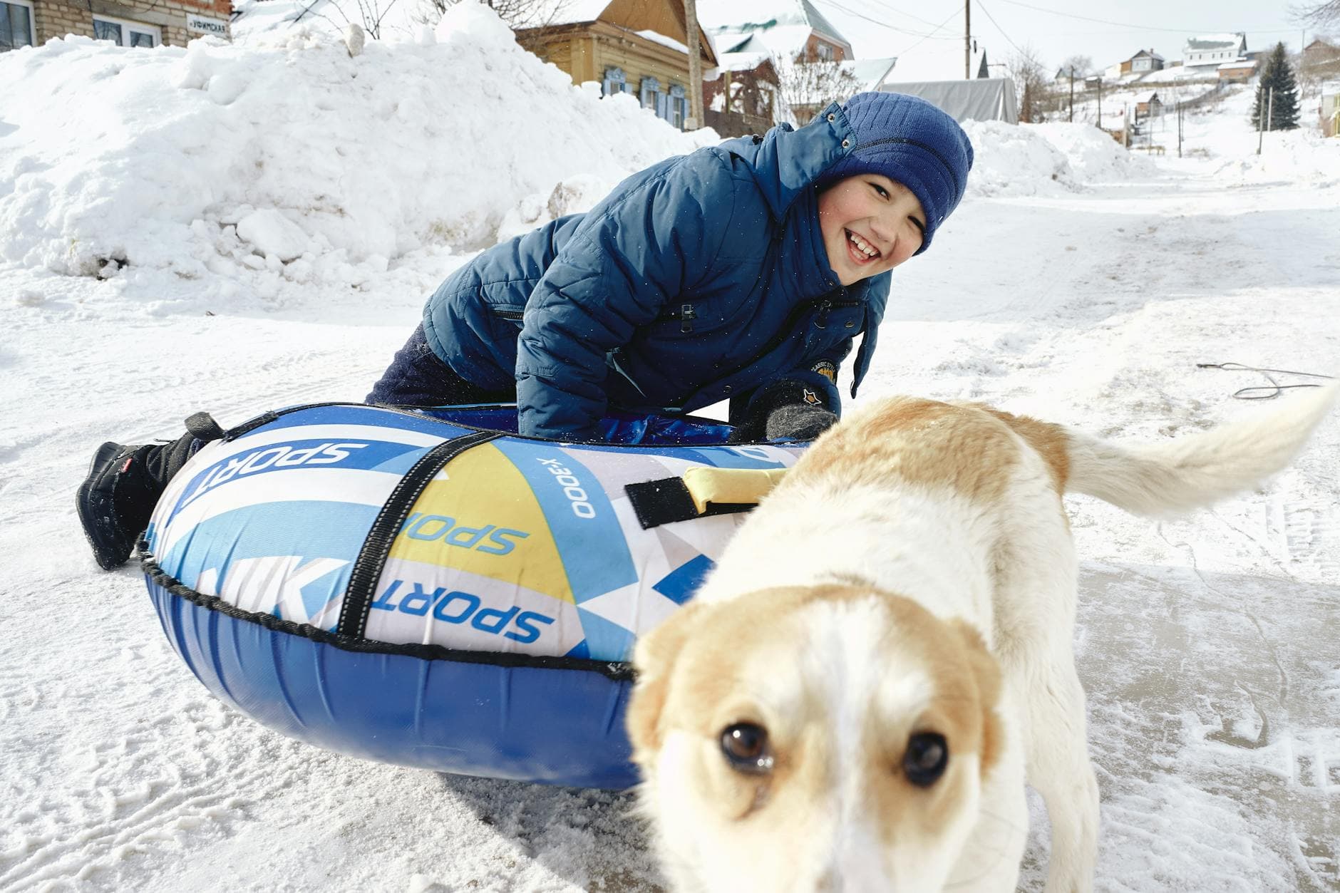 A cheerful boy playing in the snow with his dog, having winter fun outdoors.