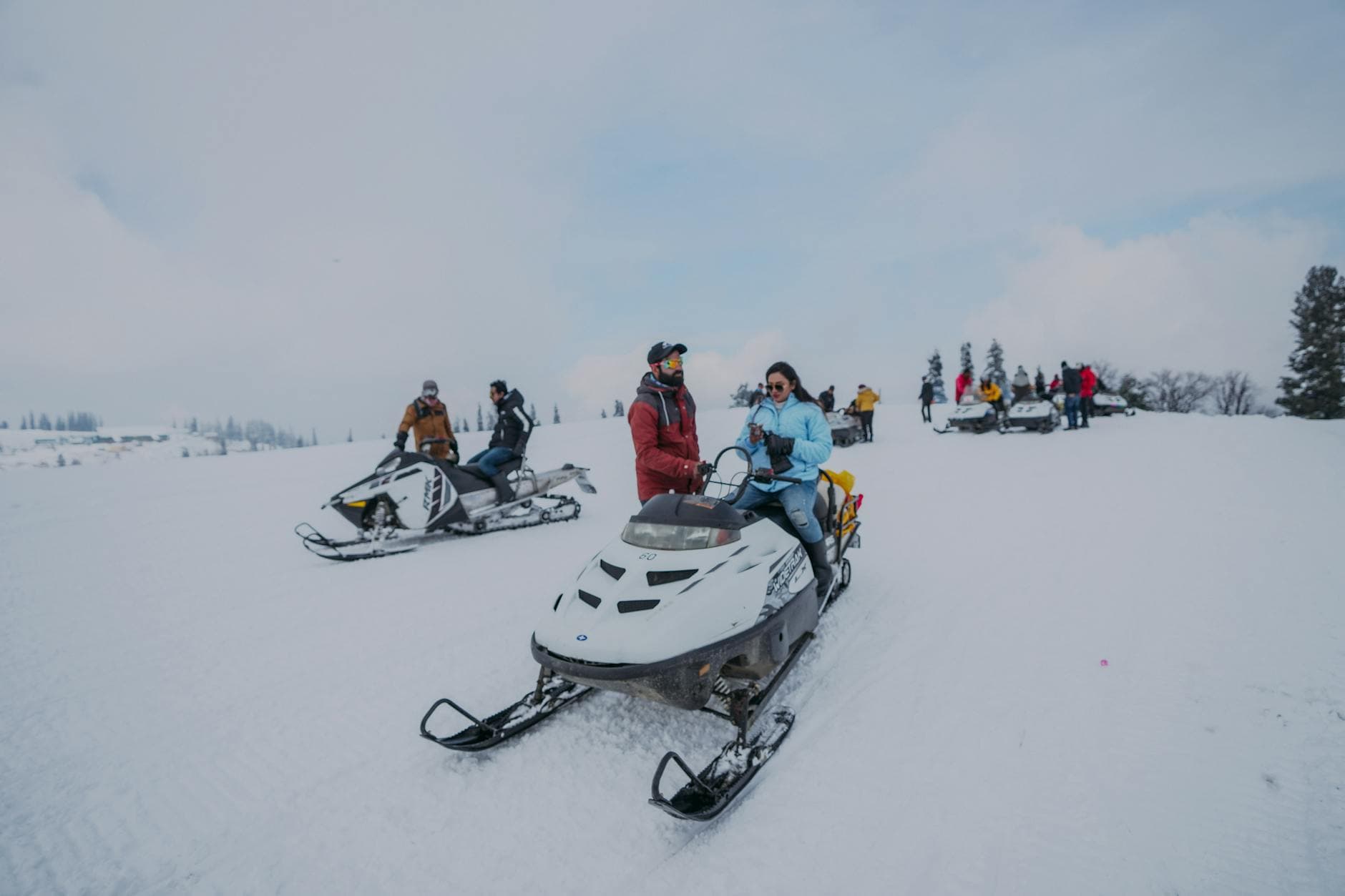 Several people enjoying a thrilling snowmobiling adventure in a winter wonderland with snowy expanses.