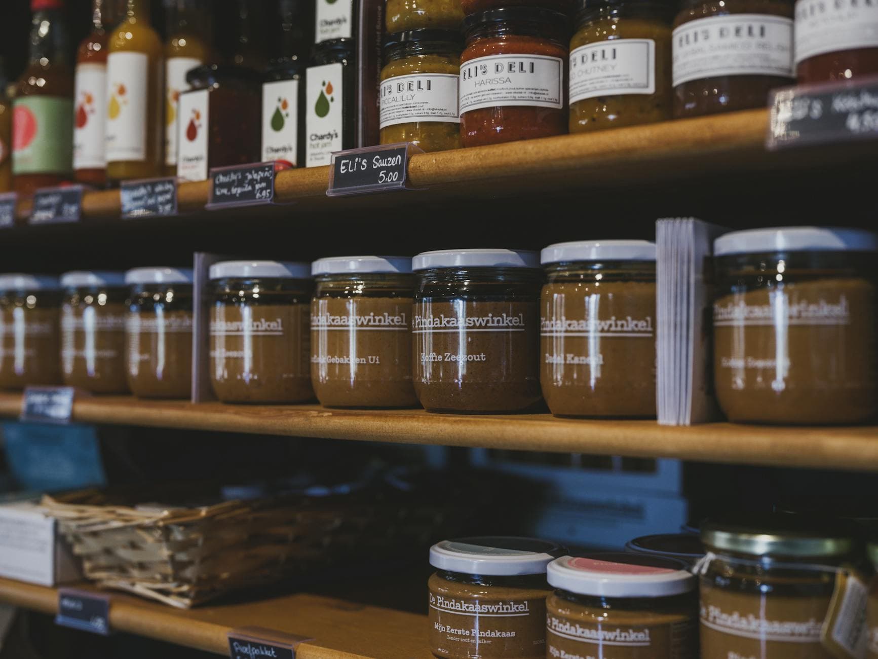 Close-up of artisanal food jars on wooden shelves in a local shop in Almere, Nederland.