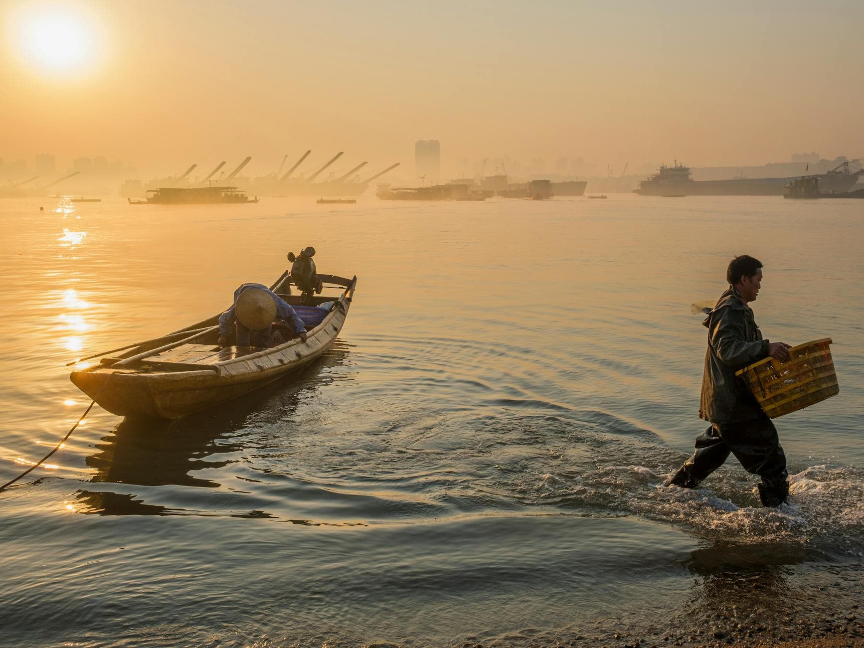 Fishermen navigating a wooden boat at sunrise, capturing early morning tranquility on the lake.
