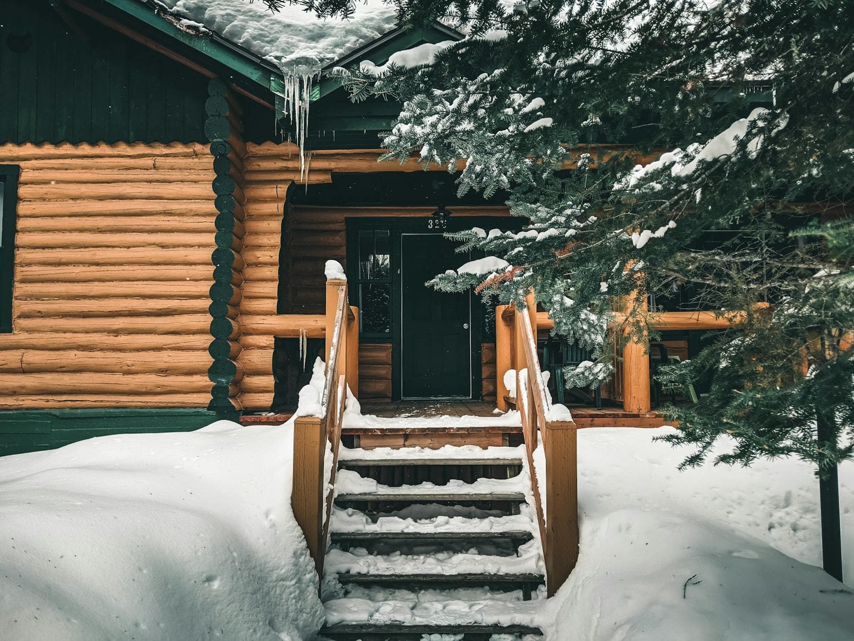 A cozy log cabin with a snowy entrance in Mont-Tremblant, Quebec.