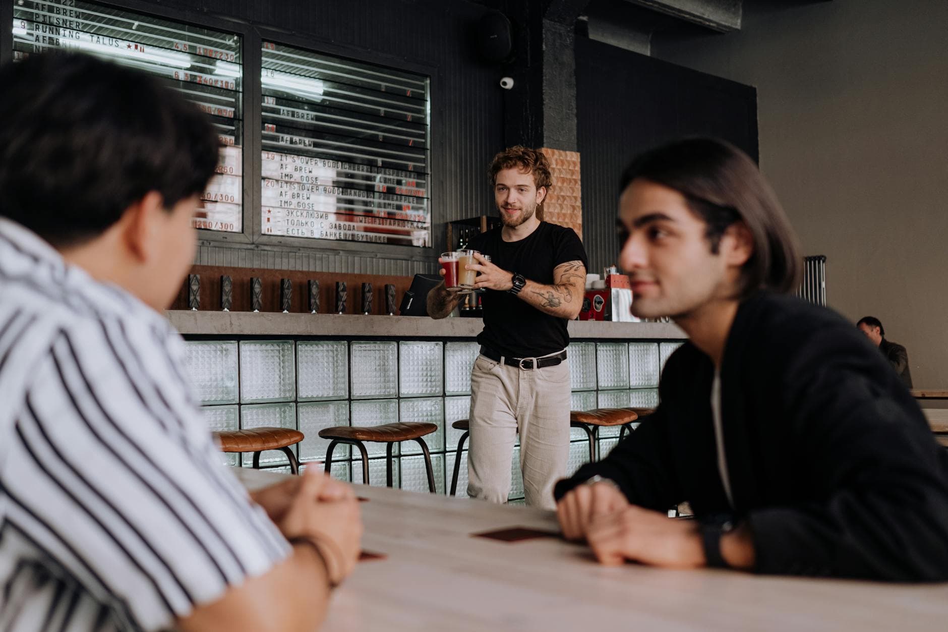 Three friends having a casual gathering at a trendy bar, enjoying drinks and conversation.