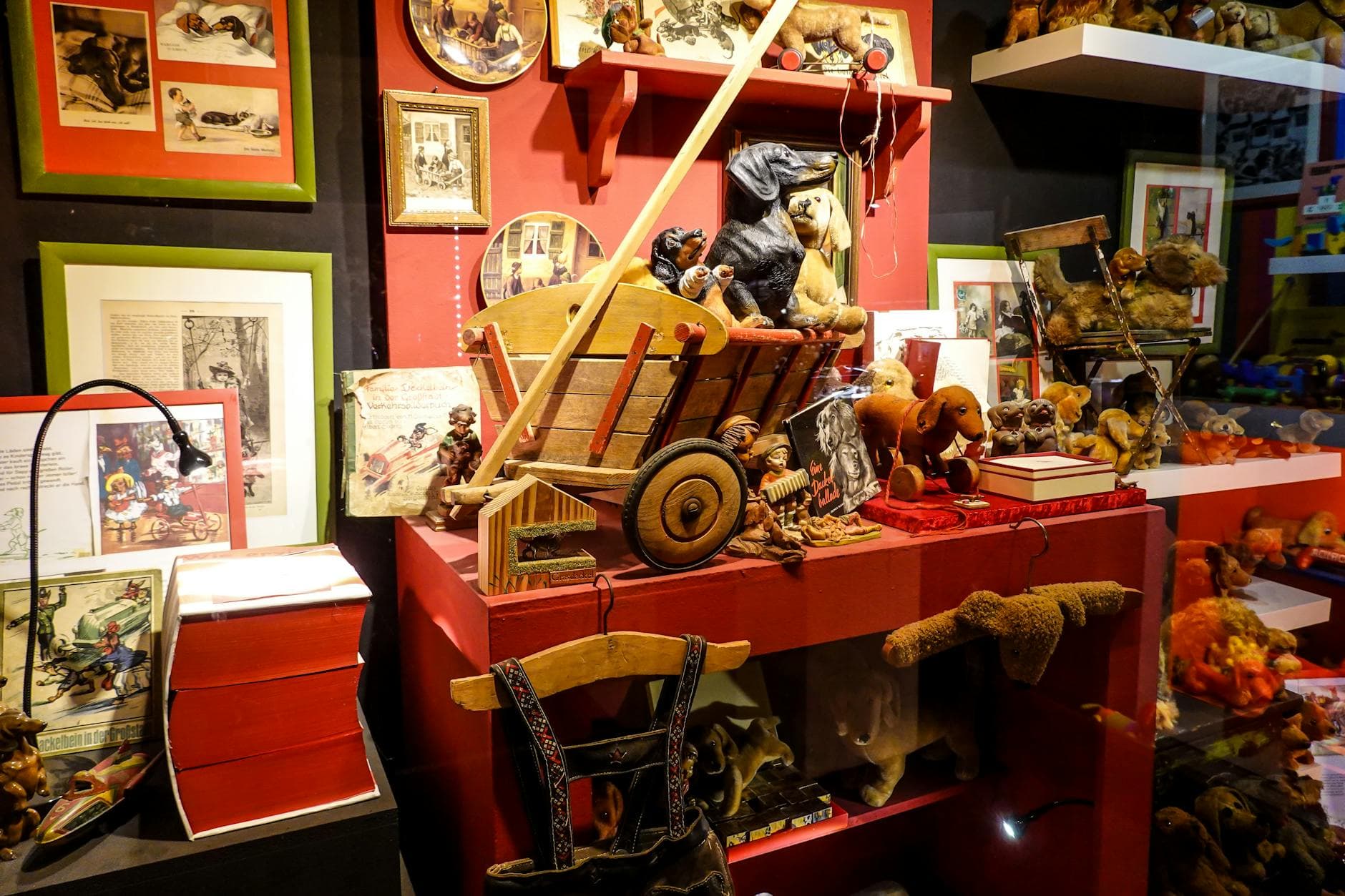 Colorful vintage toy display featuring wooden cart and figurines in museum setting.