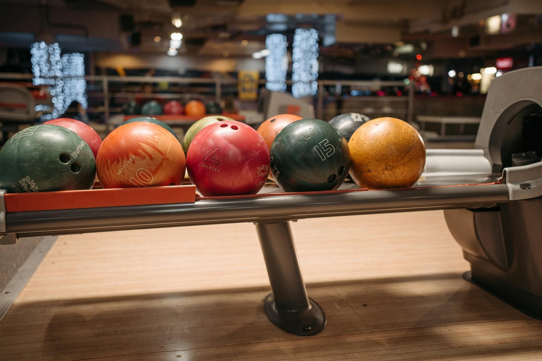 A vibrant collection of bowling balls on a return rack in an indoor bowling alley setting.