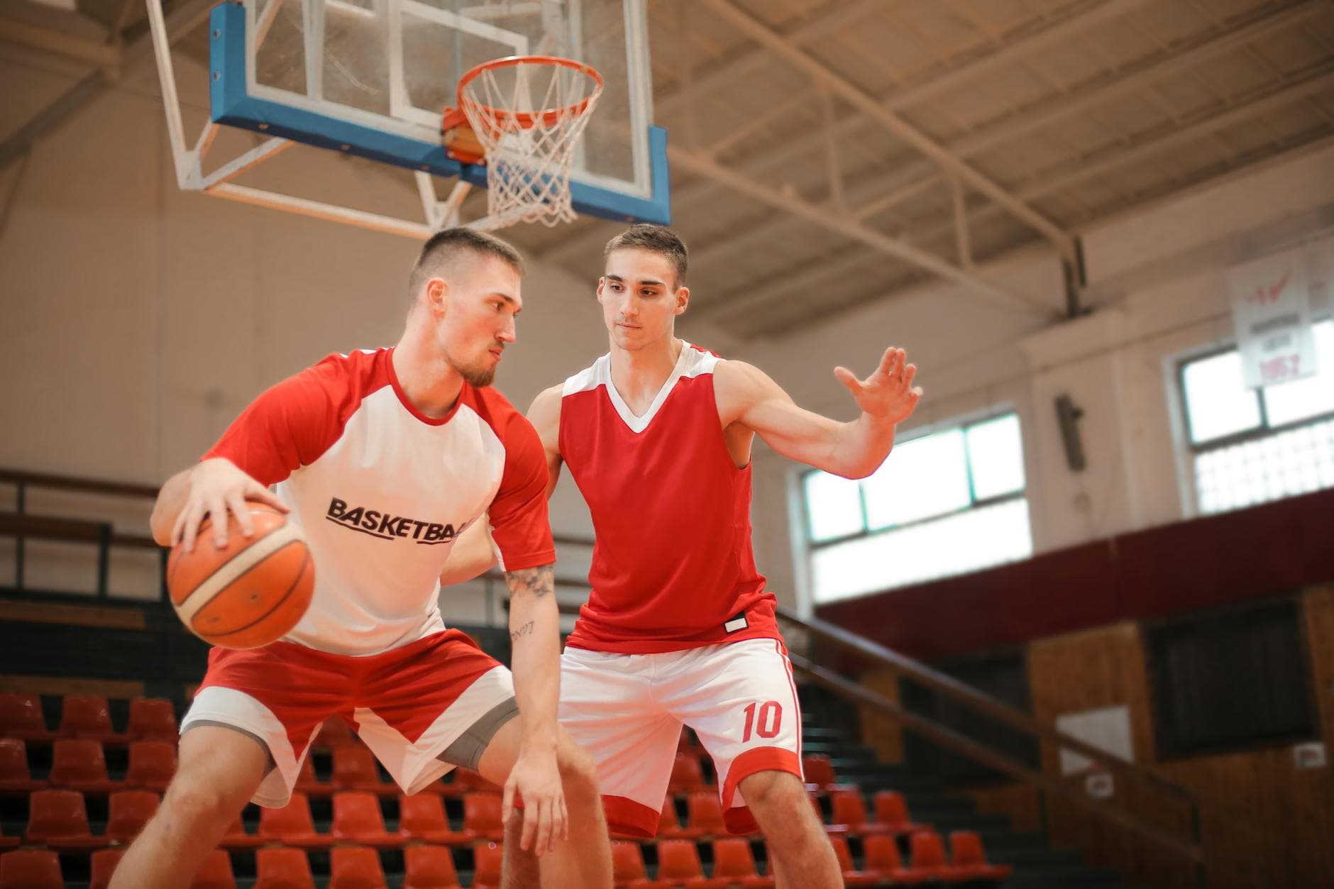 Two male basketball players practicing on an indoor court, enhancing skills and teamwork.