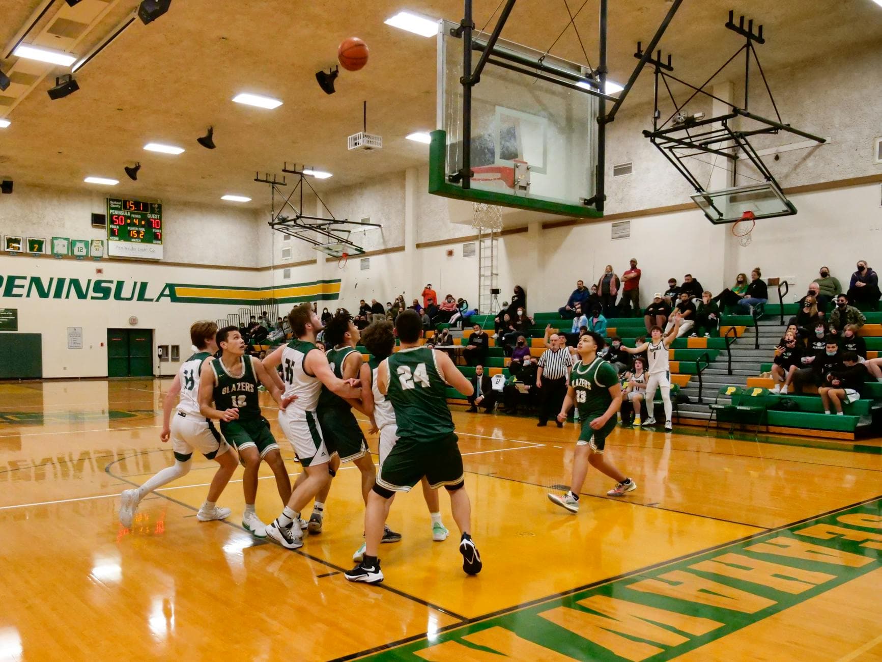 Energetic college basketball match in a gymnasium with spectators, capturing a pivotal moment near the hoop.