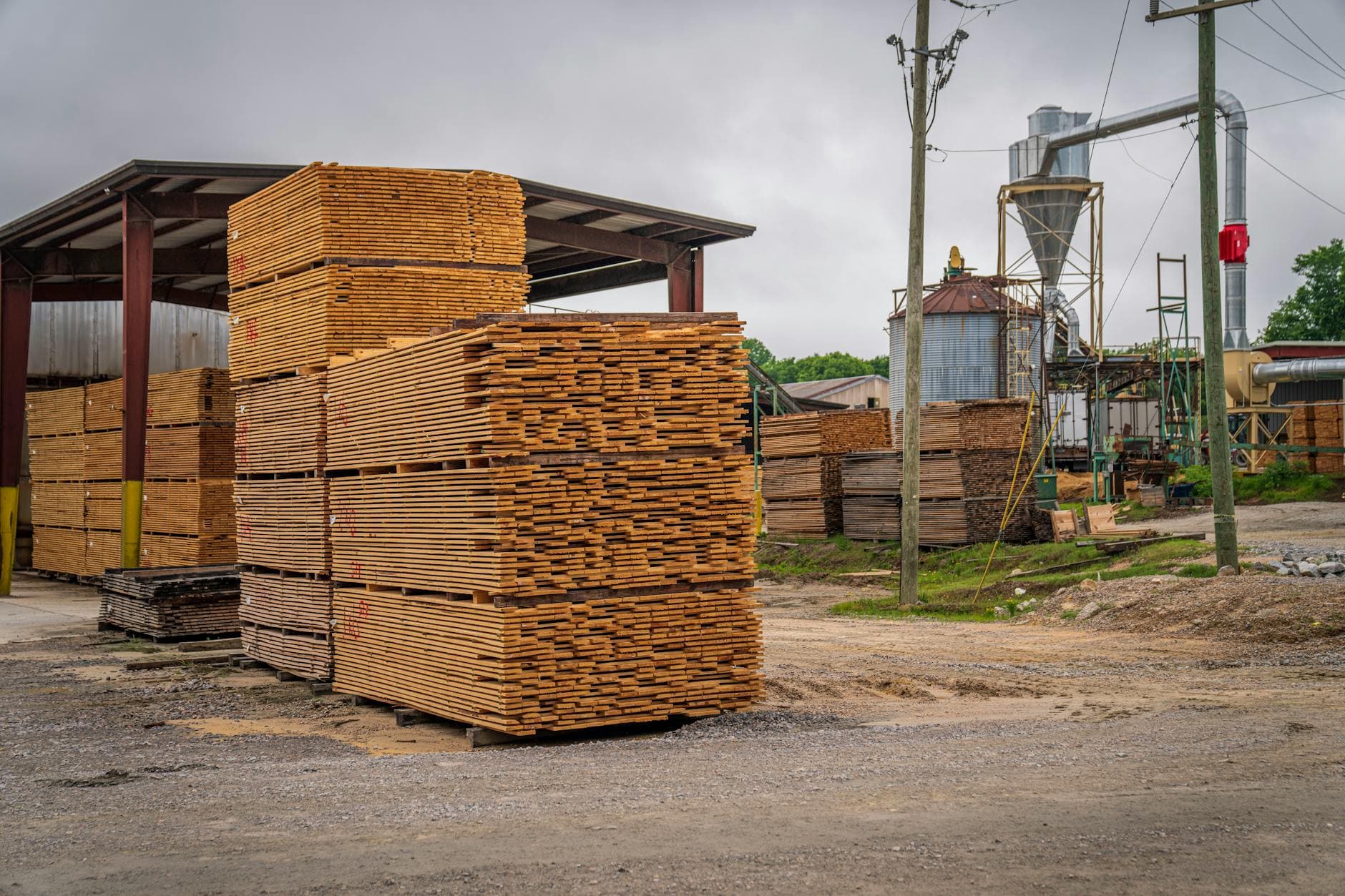 Large stacks of lumber at an outdoor sawmill processing facility.