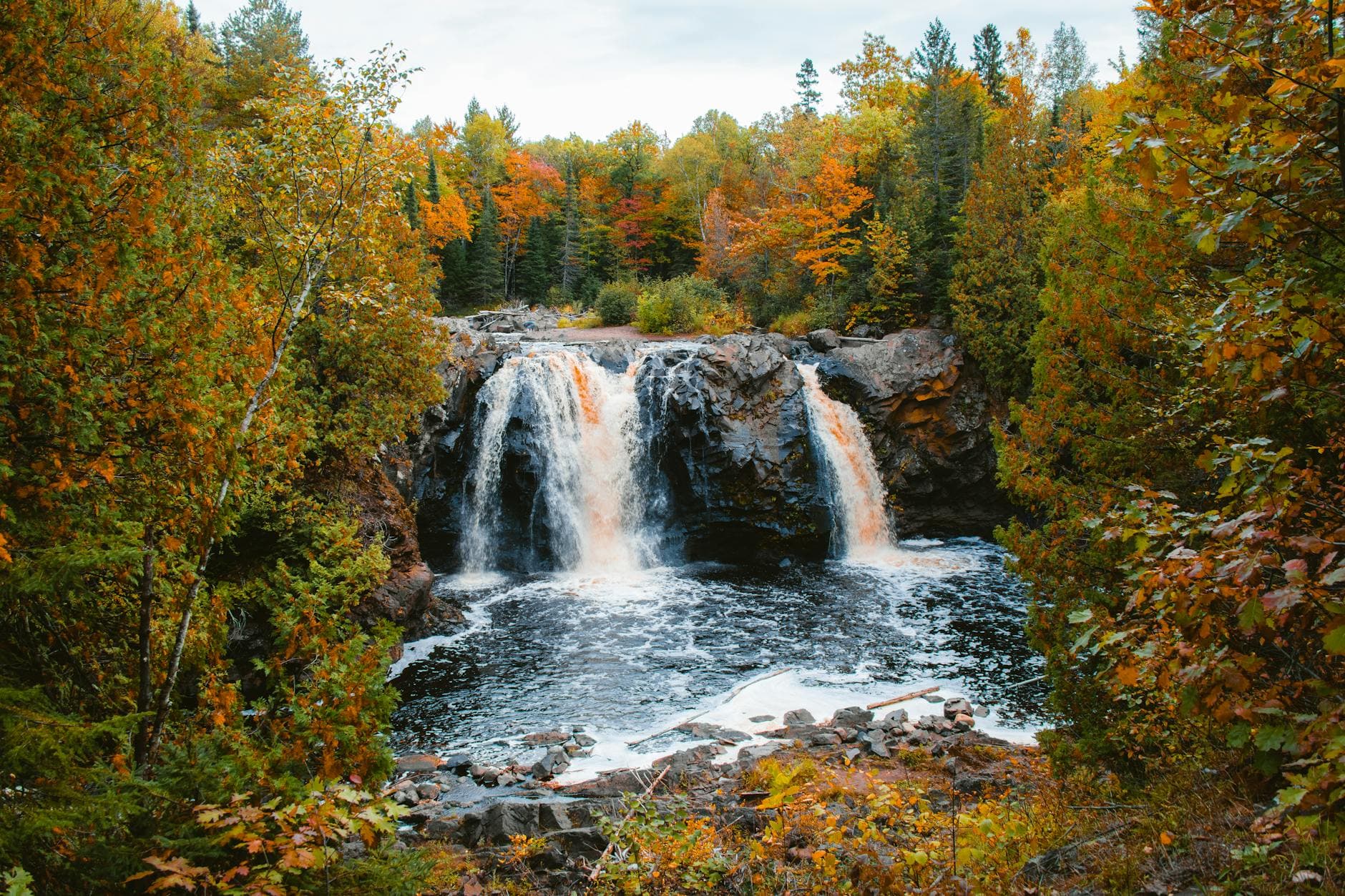 Explore the stunning waterfall surrounded by vibrant autumn foliage in Wisconsin's serene forest.