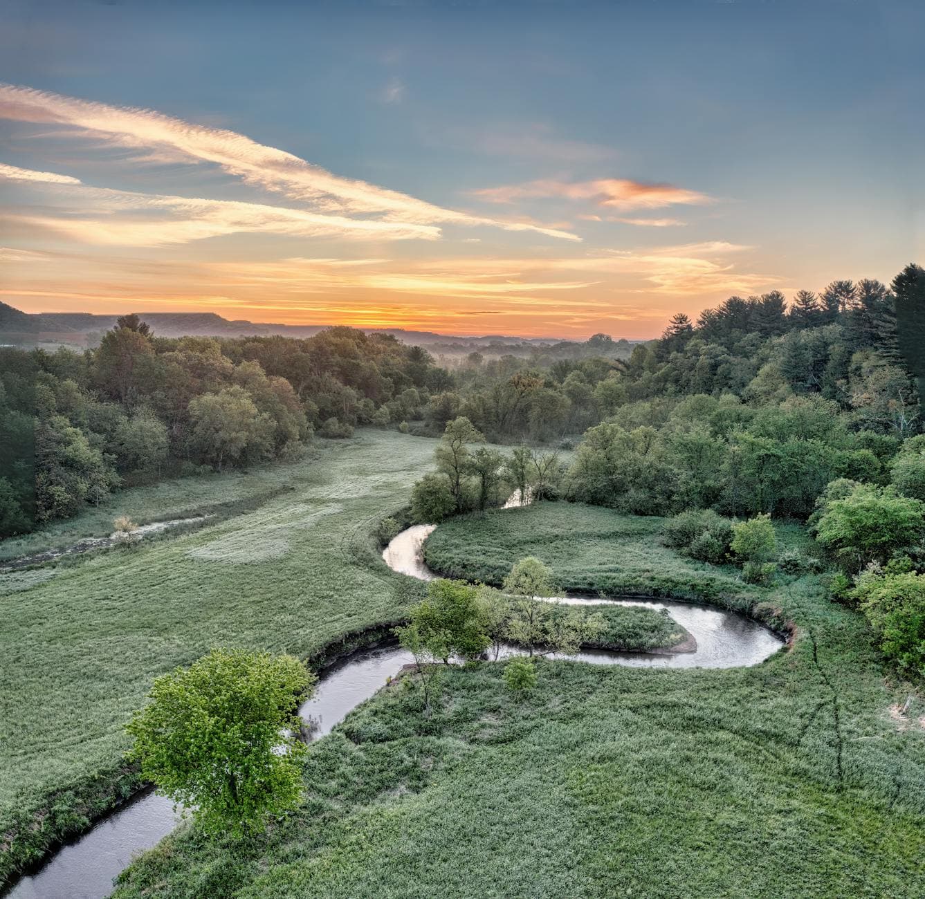 Breathtaking view of a winding river and lush forest in Misha Mokwa, Wisconsin, at sunset.