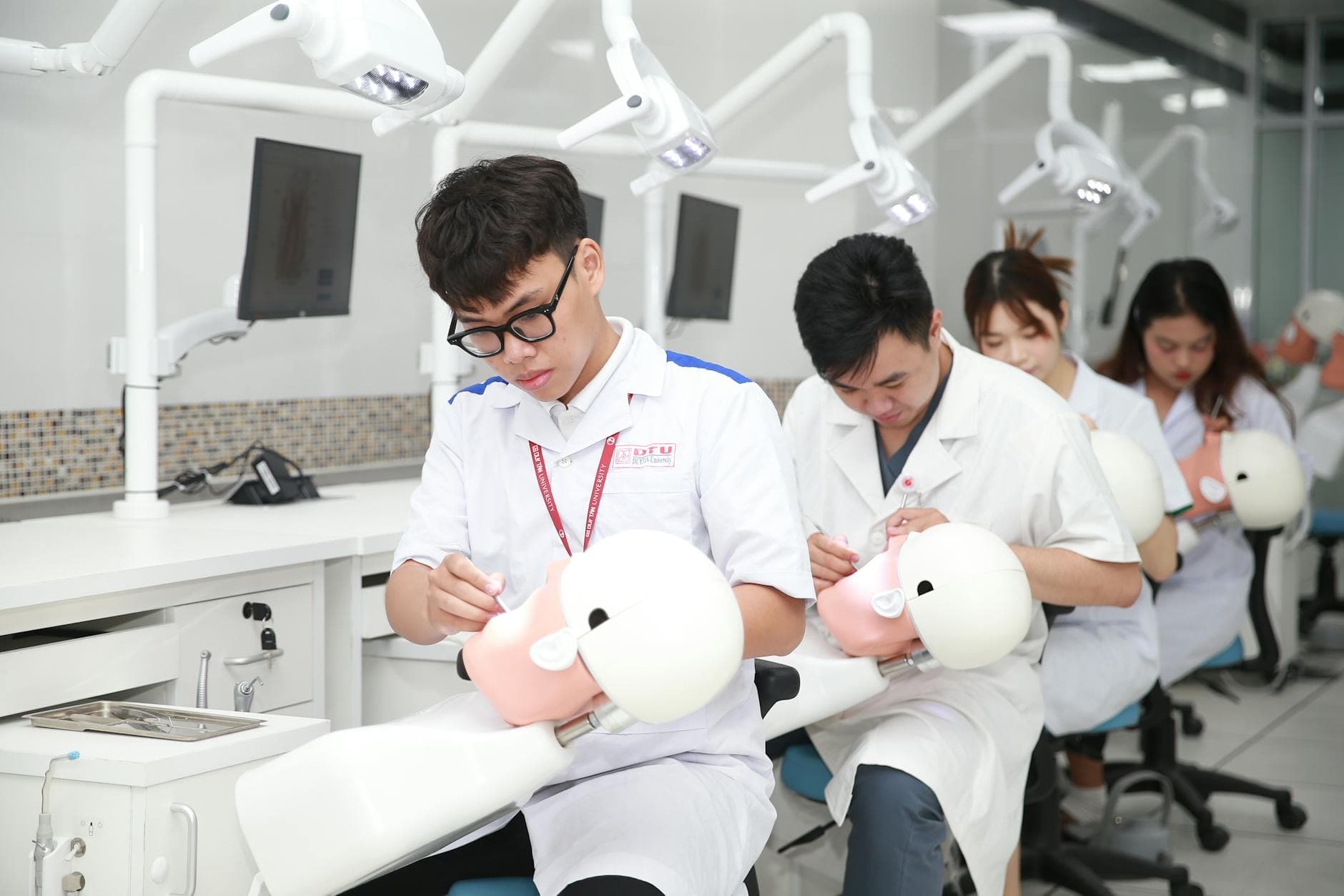 Dental students in a training lab practicing on mannequin heads for skill development.