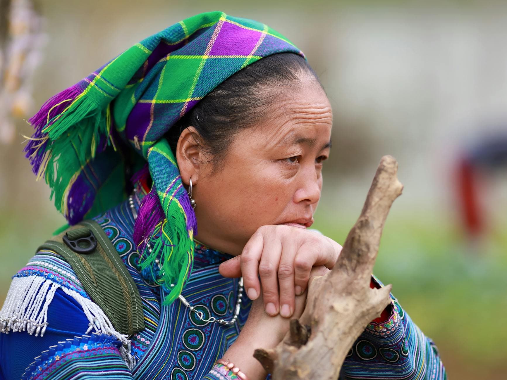 A thoughtful Hmong woman in traditional wear, Lào Cai, Vietnam.