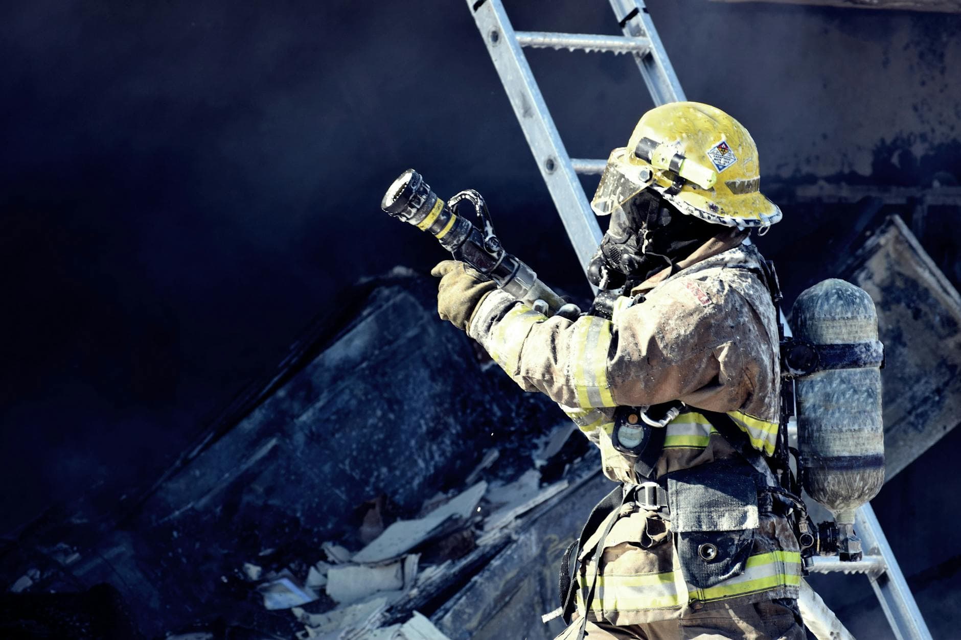 A firefighter in full gear fighting a fire with a hose, emphasizing courage and safety.